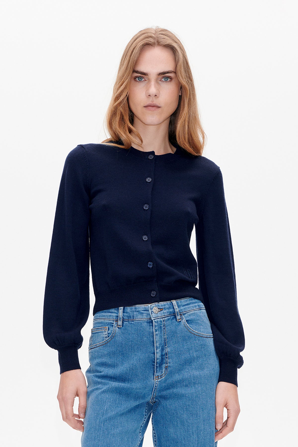 Front view of a model wearing a navy button-front cardigan with ribbed cuffs and hem, paired with light blue jeans.