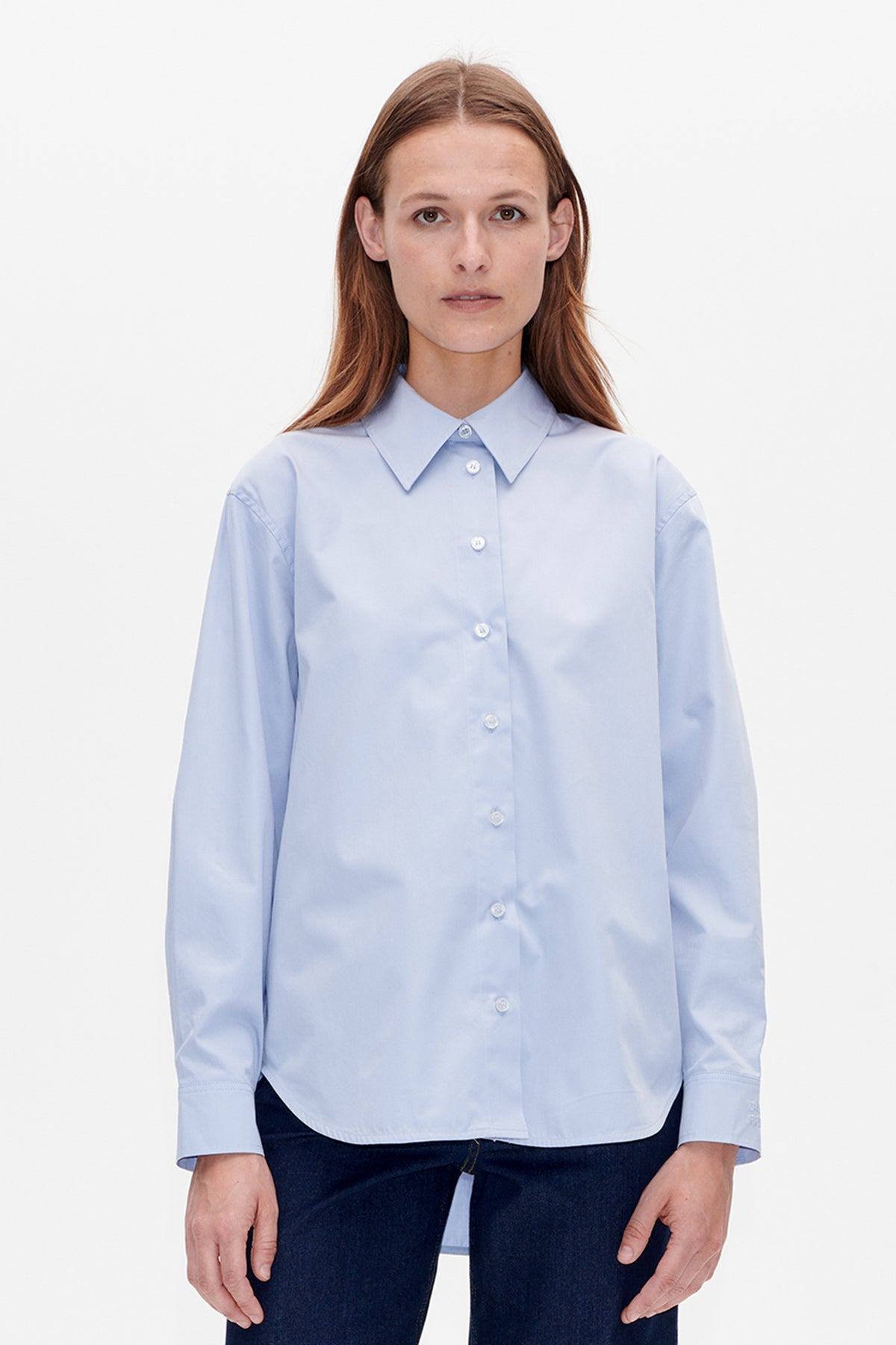 Front view of a model wearing a pale blue long-sleeved button-up shirt with a pointed collar and white buttons.