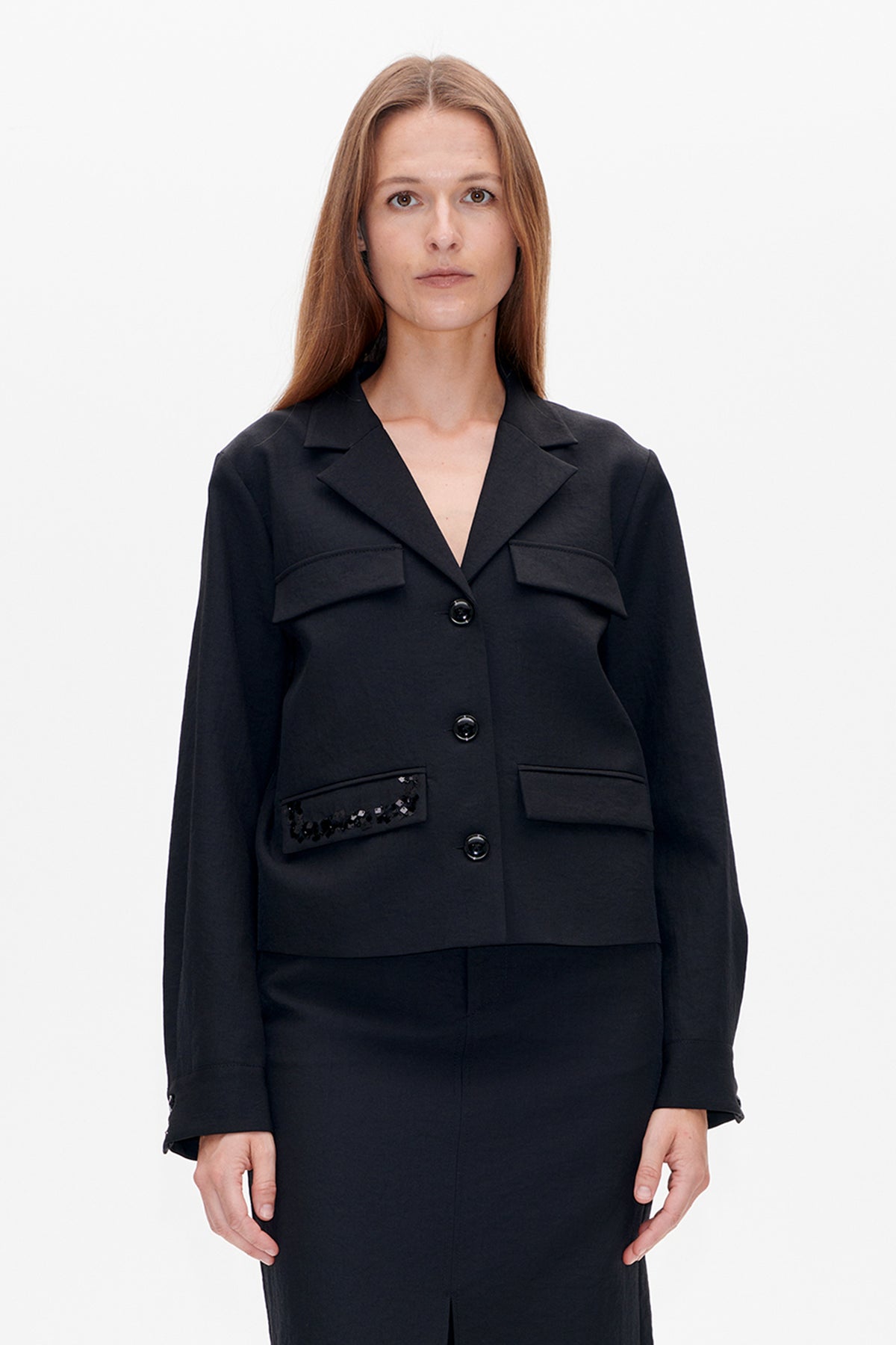 Front view of a black longline blazer with notched lapels, button fastening, flap pockets and sequined detail on one pocket.