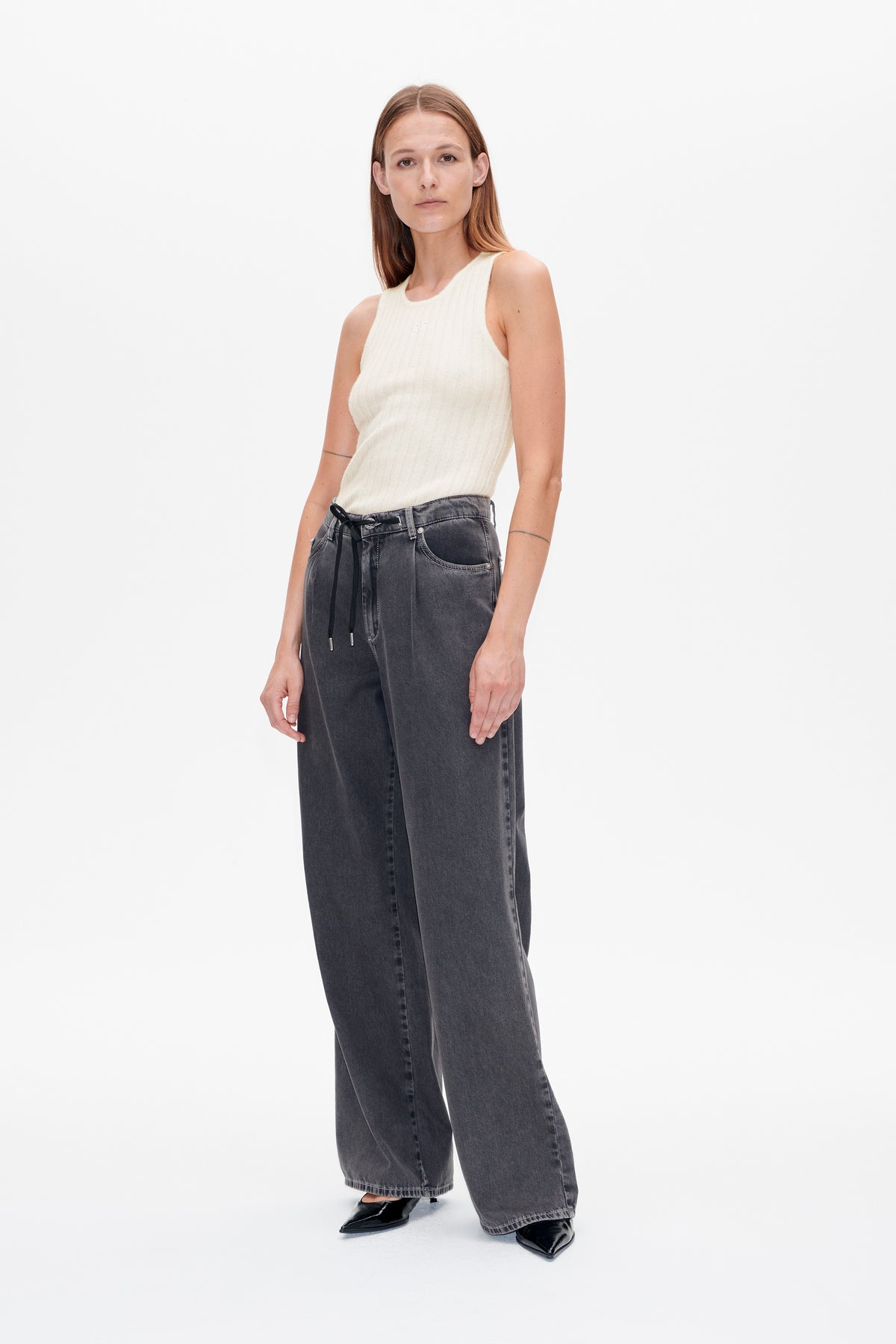 Front view of a model wearing an ivory ribbed sleeveless top with charcoal wide-leg jeans and a black drawstring belt.