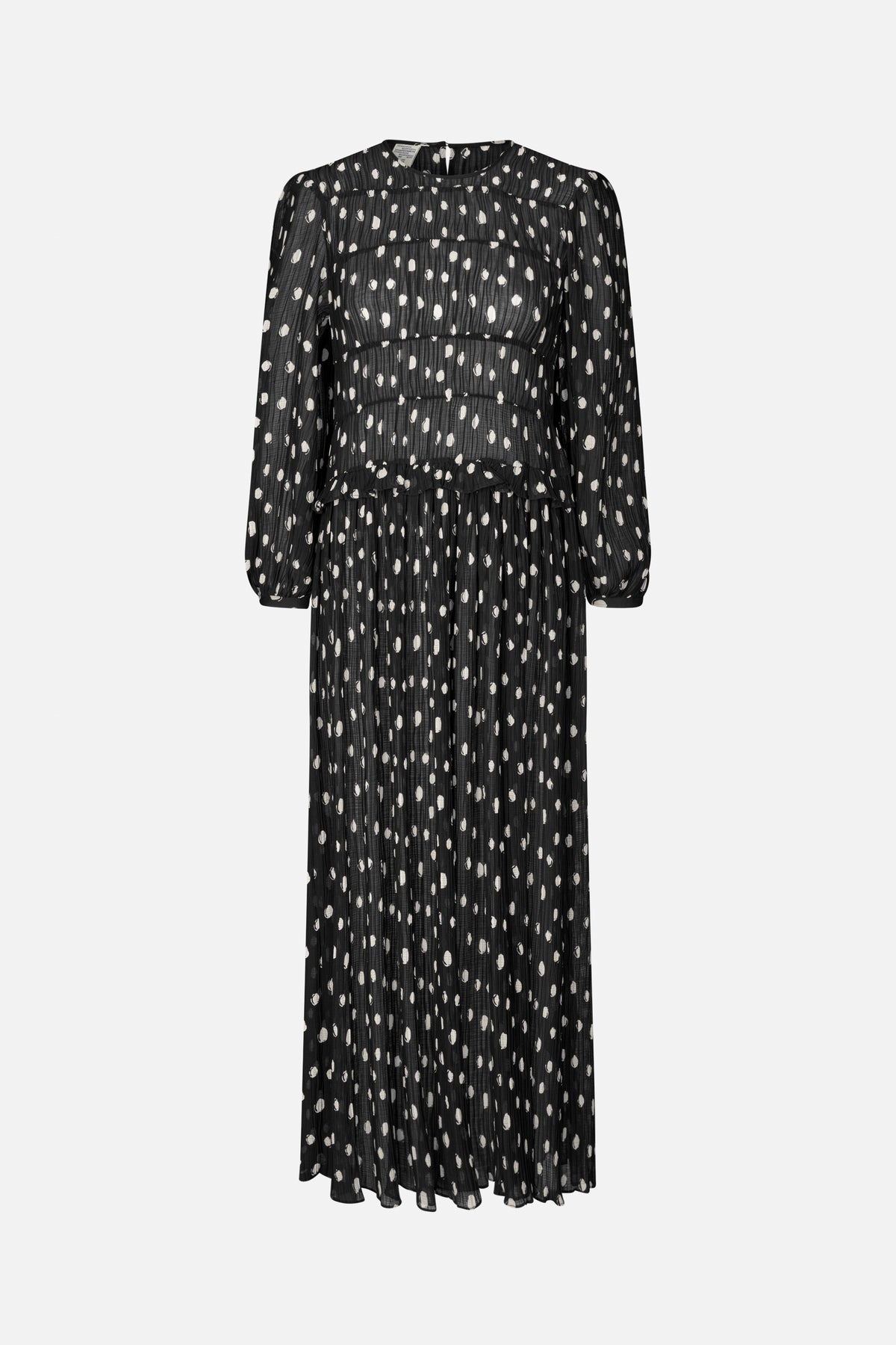 Front view of a long black pleated dress with scattered white abstract spots, long sleeves, a round neckline and a ruffled waist seam.