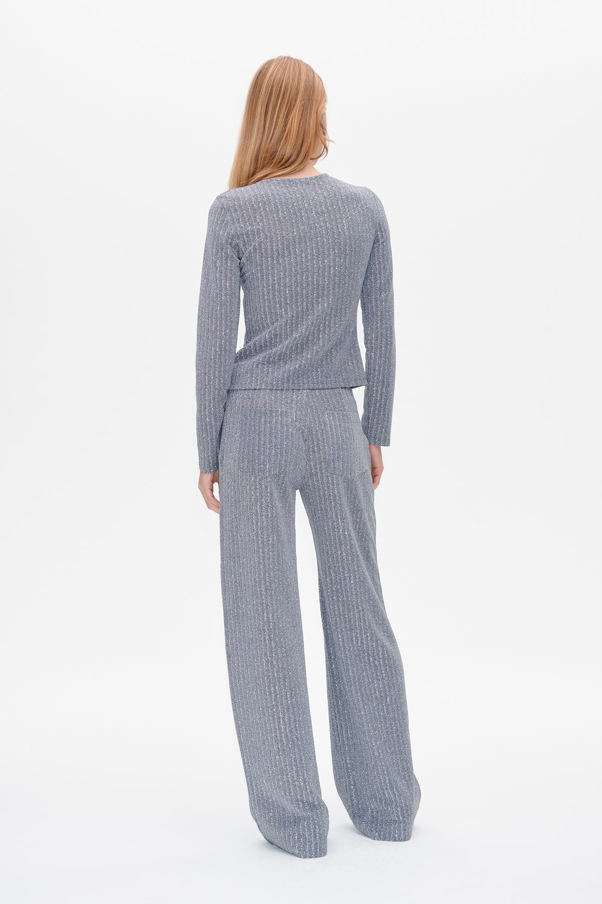 Back view of a model wearing a grey long-sleeved ribbed top and matching wide-leg trousers with subtle vertical flecks.