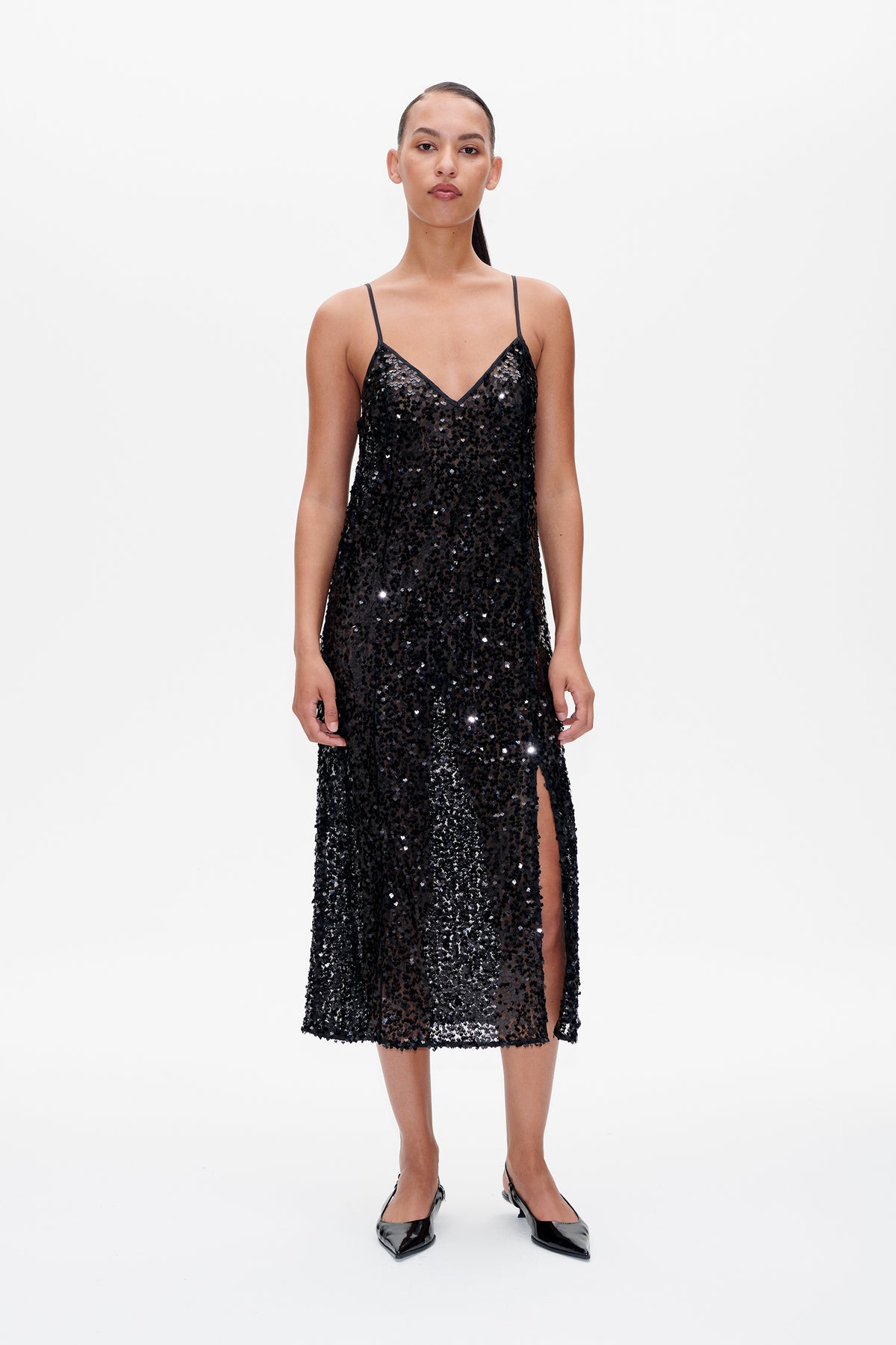 Front view of a black spaghetti-strap dress covered in reflective sequins, with a V-neckline and side slit.