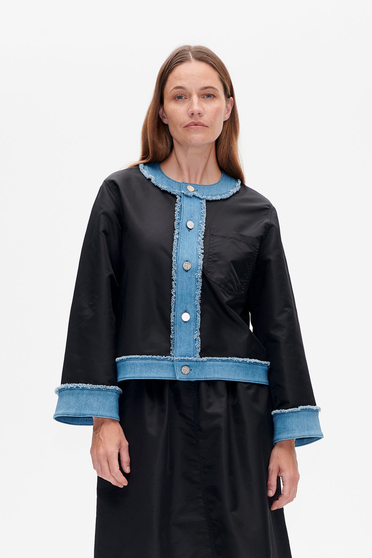 Front view of a black long-sleeved dress with blue denim trim, frayed edges, a buttoned placket, cuffs and waist band.