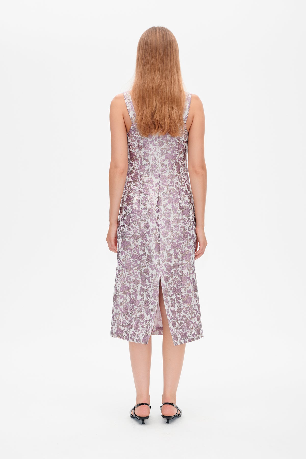 Back view of a sleeveless midi dress with a pale lilac and mauve floral print, centre seam and back slit.