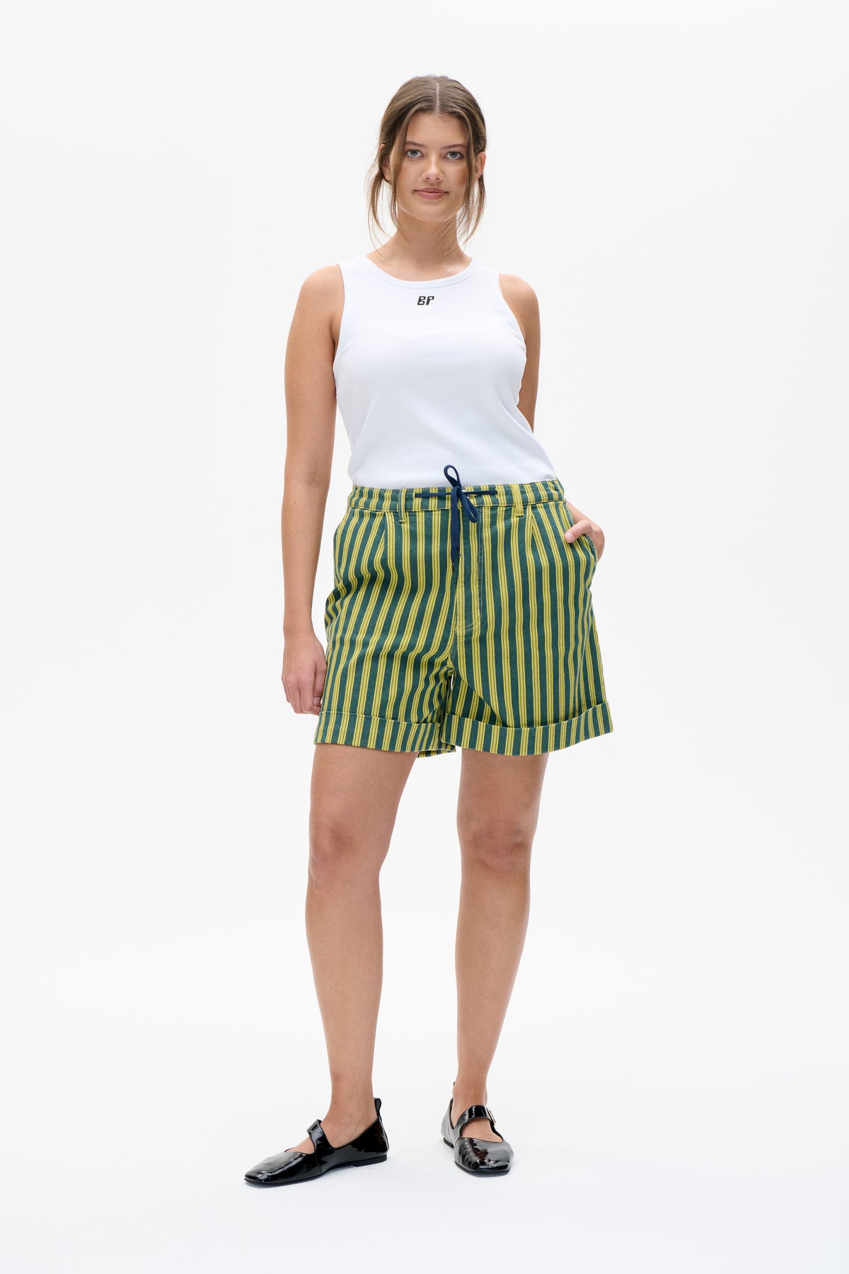 Front view of a white sleeveless top with a small chest logo, paired with green and yellow striped shorts.