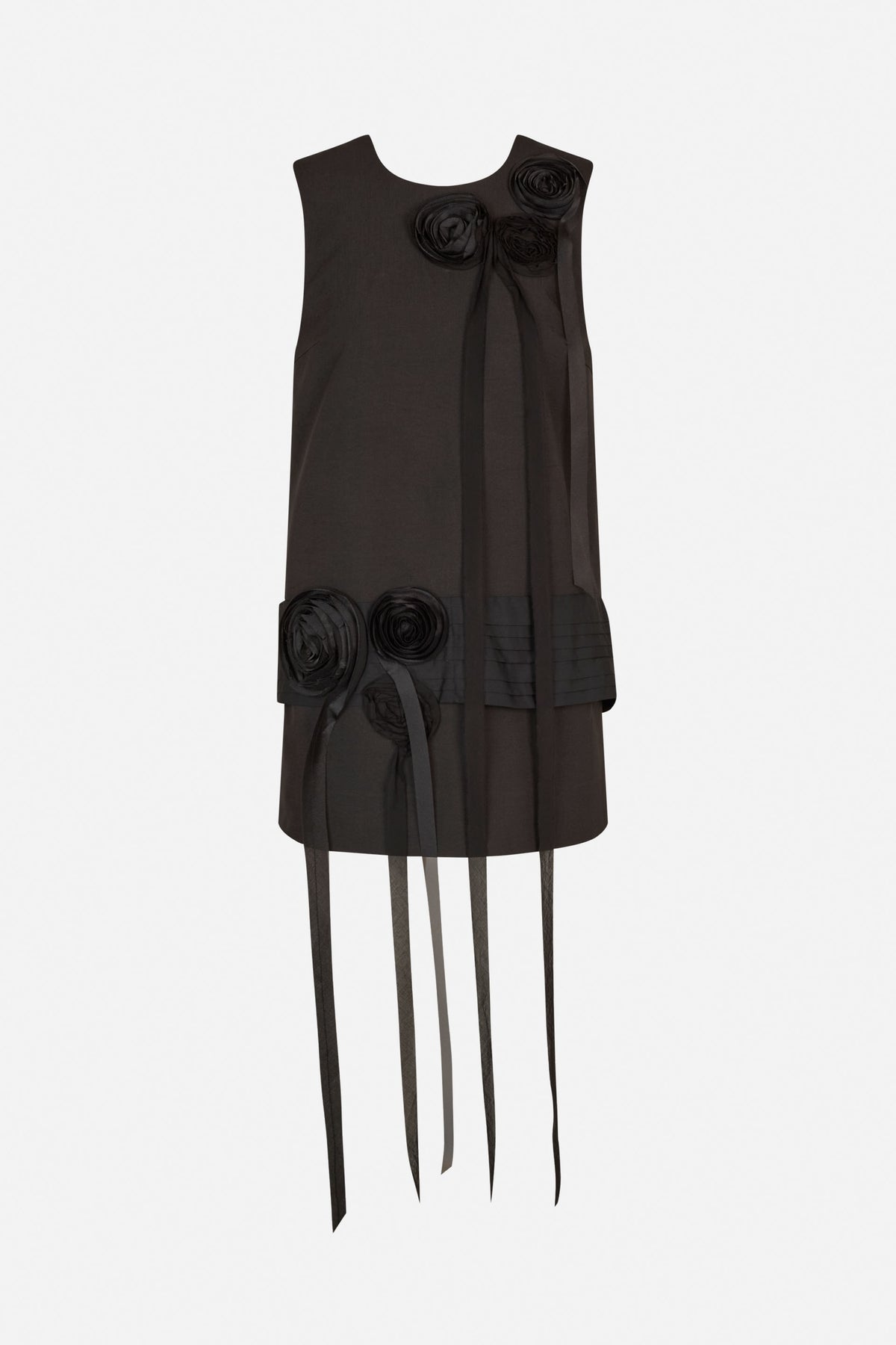 Front view of a black sleeveless dress with sculptural rosette details, pleated hem panels and long hanging ribbons.