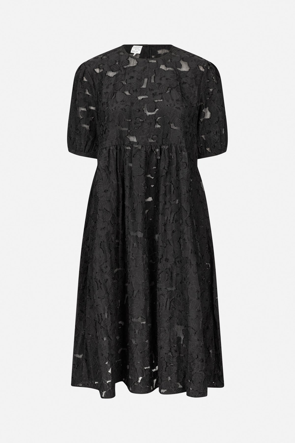 Front view of a black dress with short puff sleeves, a gathered waist, and textured floral fabric with sheer cutout details.