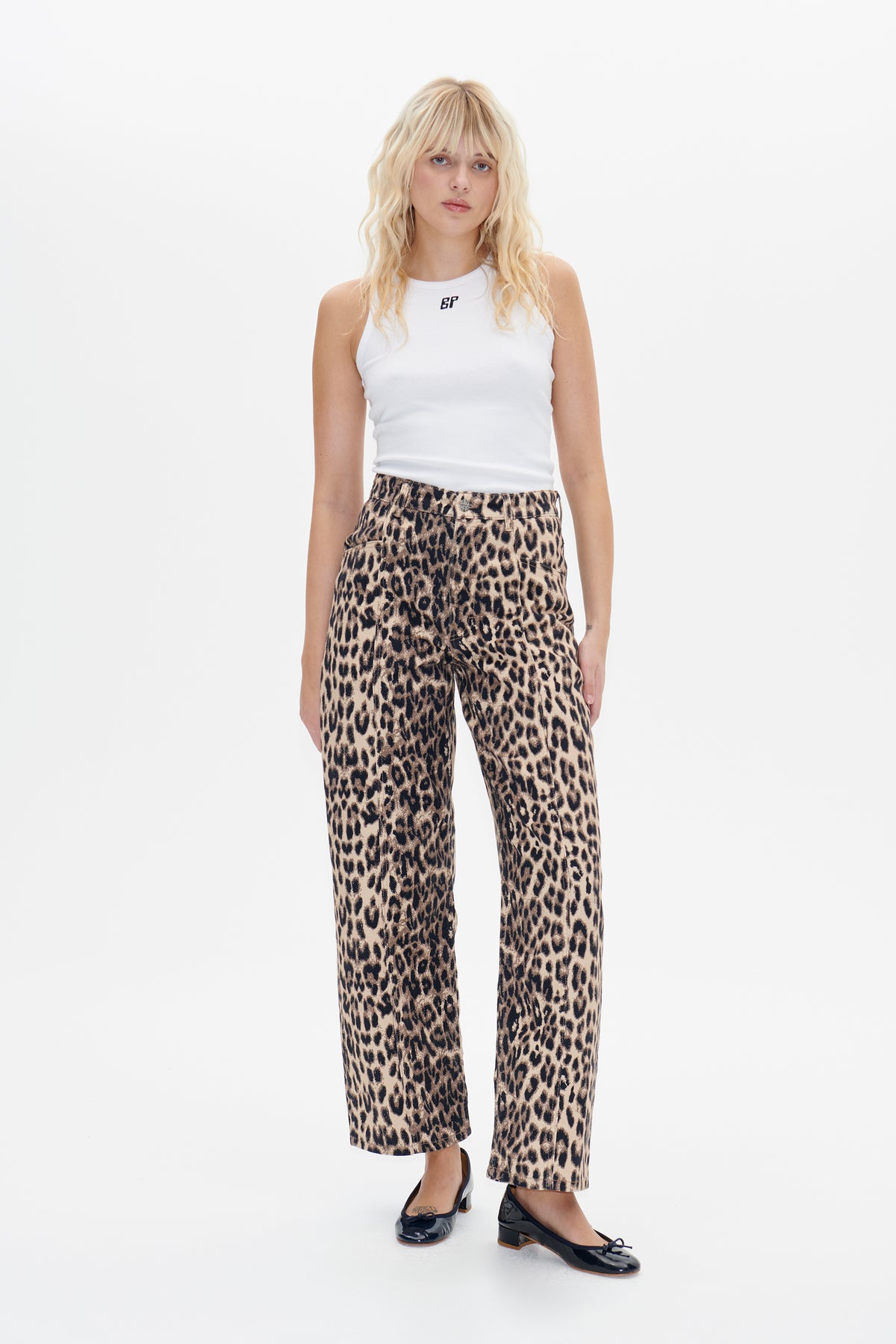 Front view of a model wearing a white sleeveless top with a small chest logo and beige-and-black leopard-print wide-leg trousers.