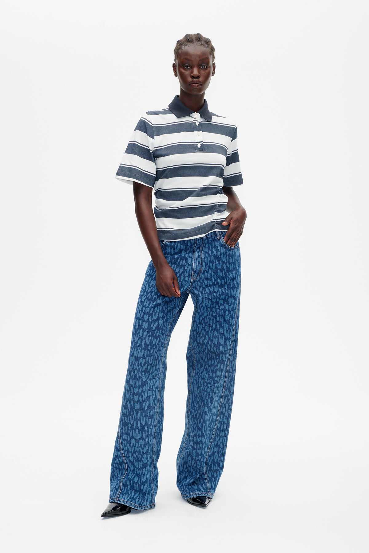 Model wearing a navy and white striped short-sleeve polo with wide-leg blue patterned jeans, front view.