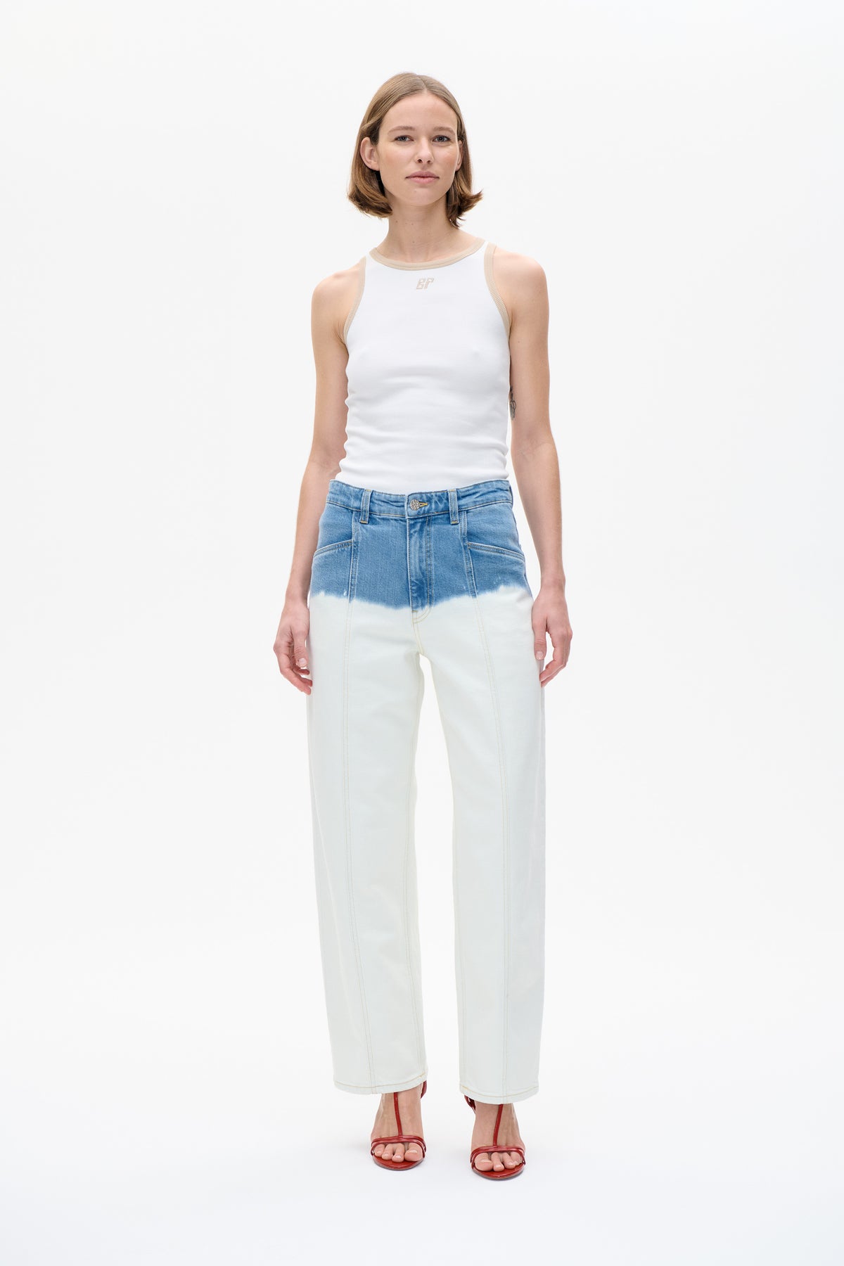 Model wearing a white sleeveless top with beige trim and a small BP emblem, paired with blue-to-off-white wide-leg jeans.