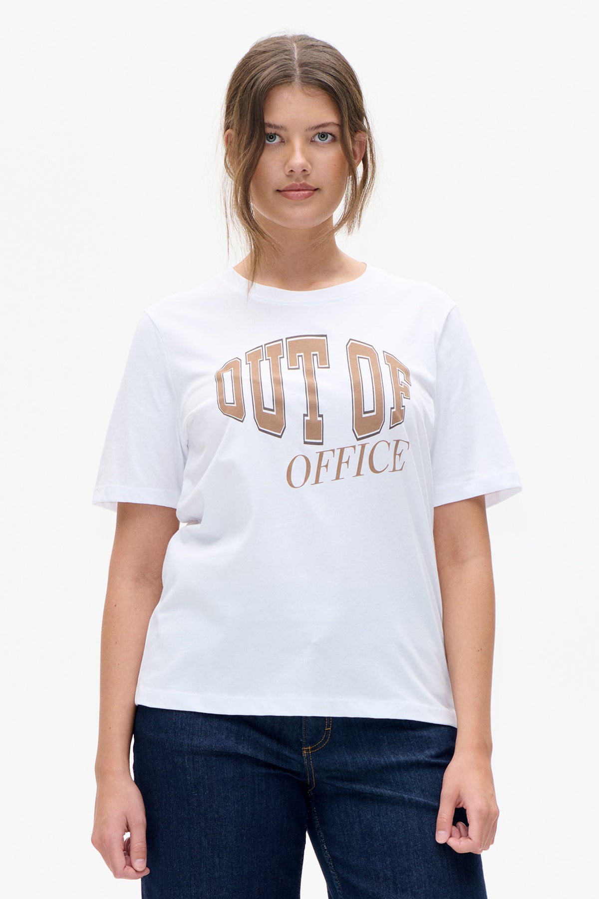Front view of a white short-sleeved T-shirt with tan collegiate-style “OUT OF OFFICE” lettering, worn with dark jeans.