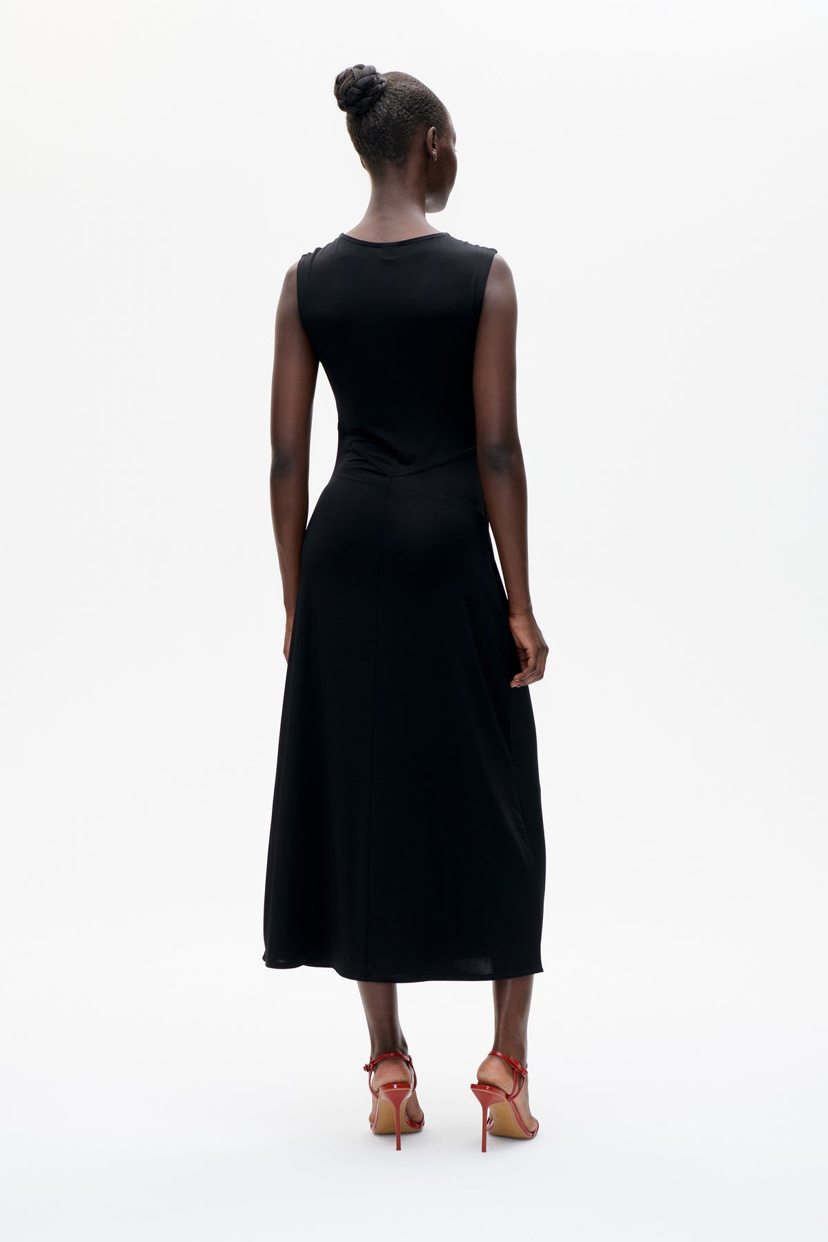 Back view of a model wearing a black sleeveless, crew-neck midi dress with a fitted waist and flared skirt.