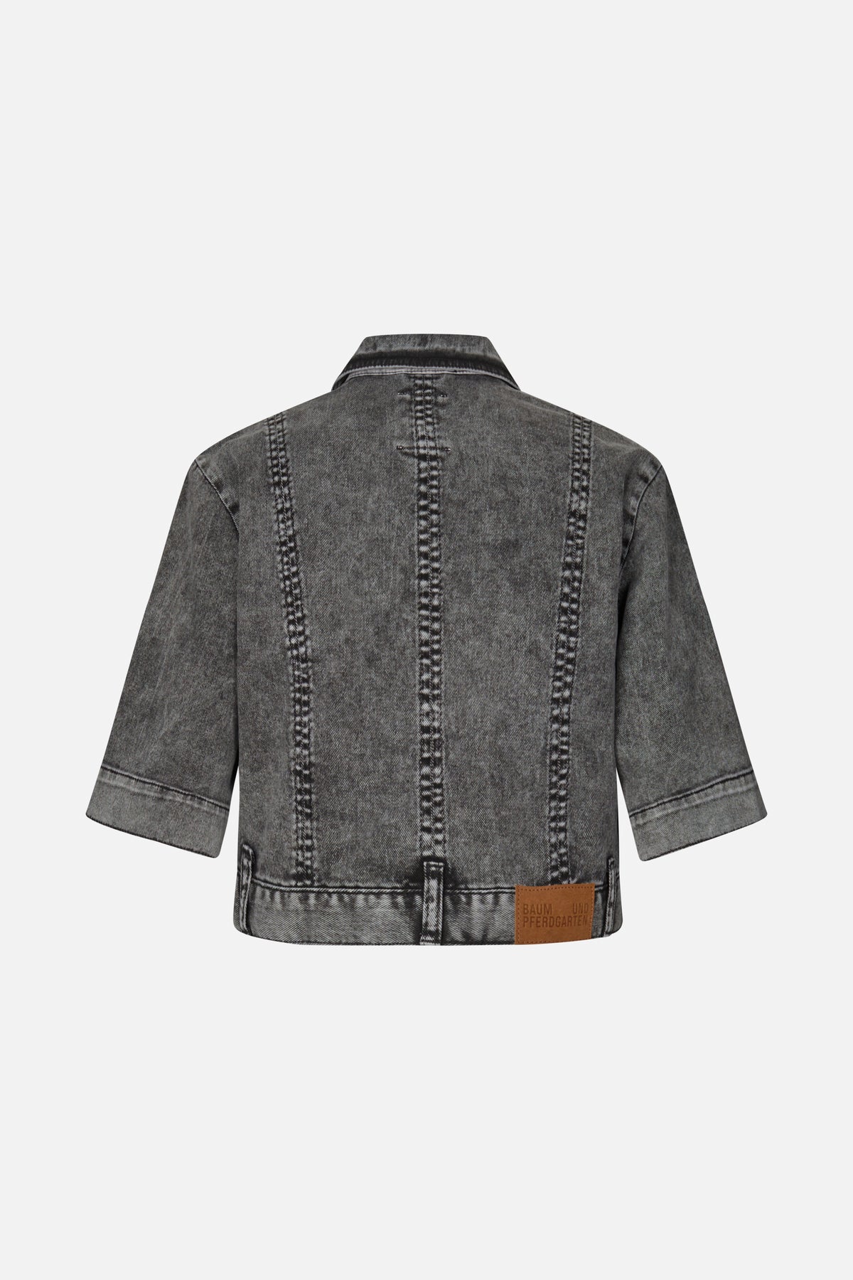 Back view of a charcoal grey washed denim jacket with elbow-length sleeves, prominent vertical contrast seams and a brown hem patch.
