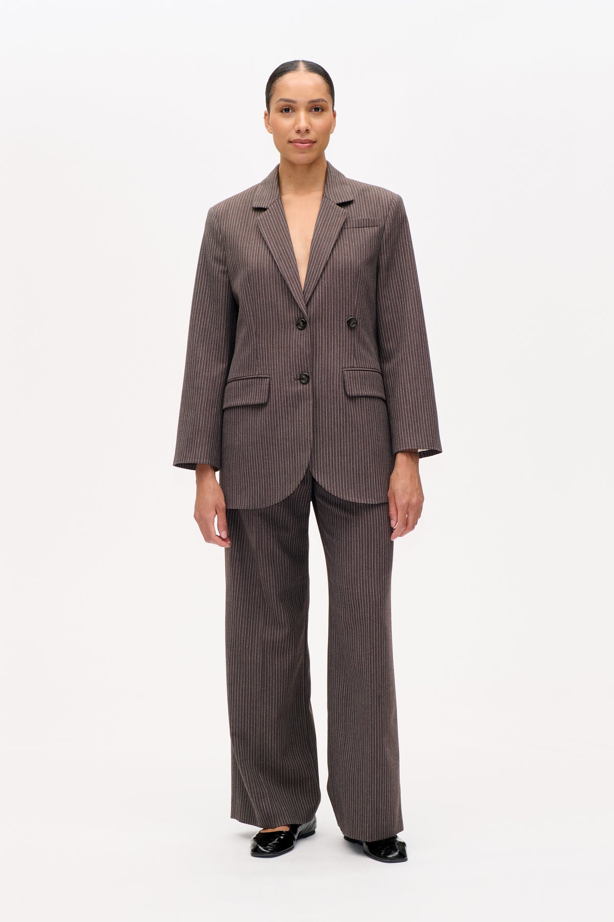 Front view of a model wearing a brown pinstripe double-breasted blazer with matching wide-leg trousers.