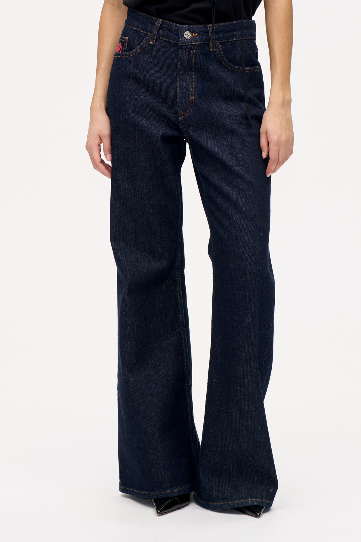 Front view of dark indigo wide-leg jeans with contrast stitching, a button waist, and a small pink detail on the coin pocket.