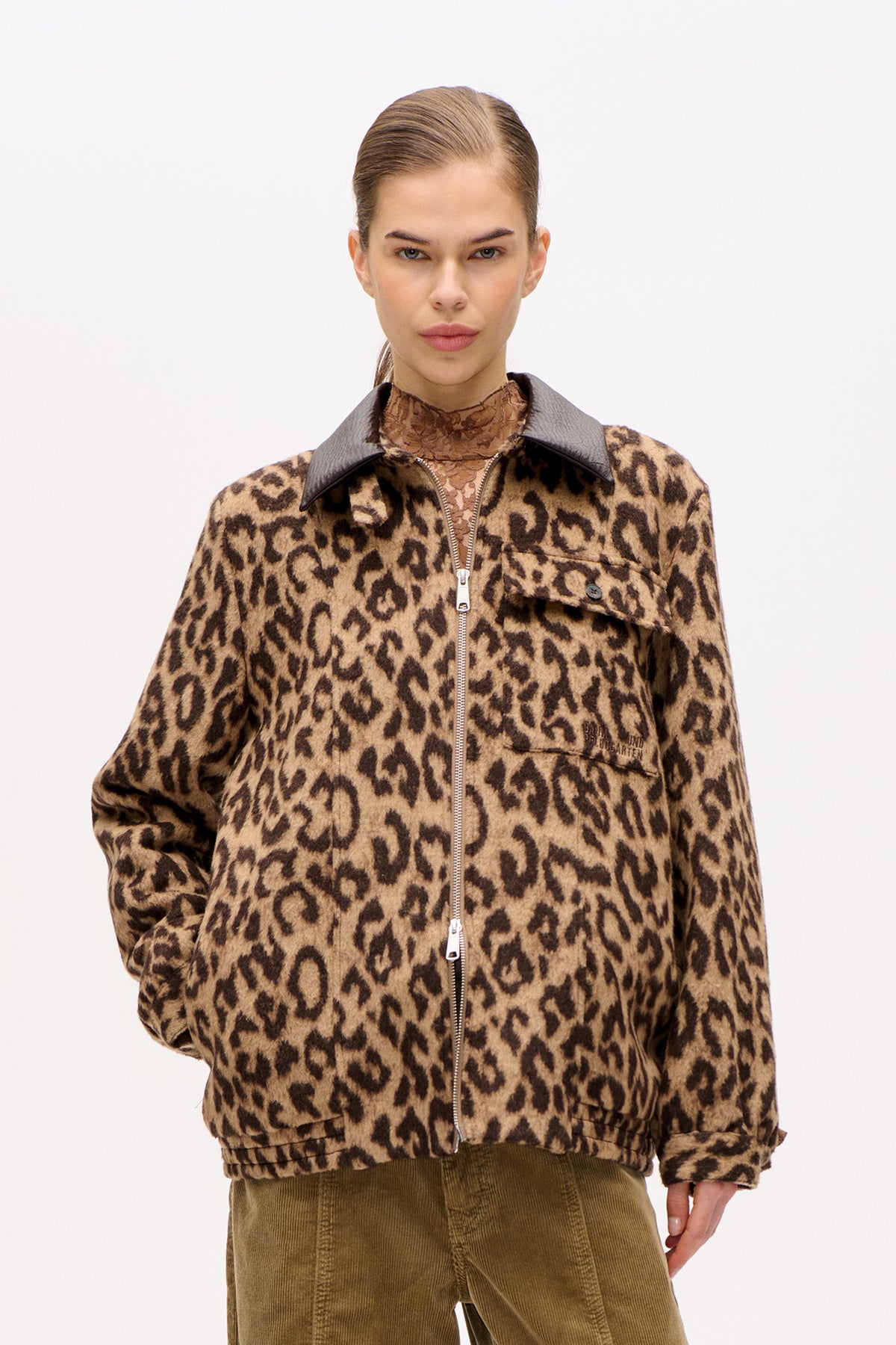 Front view of a tan and dark brown leopard-print jacket with a zip fastening, large grey collar and flap chest pocket, worn over a brown patterned top.