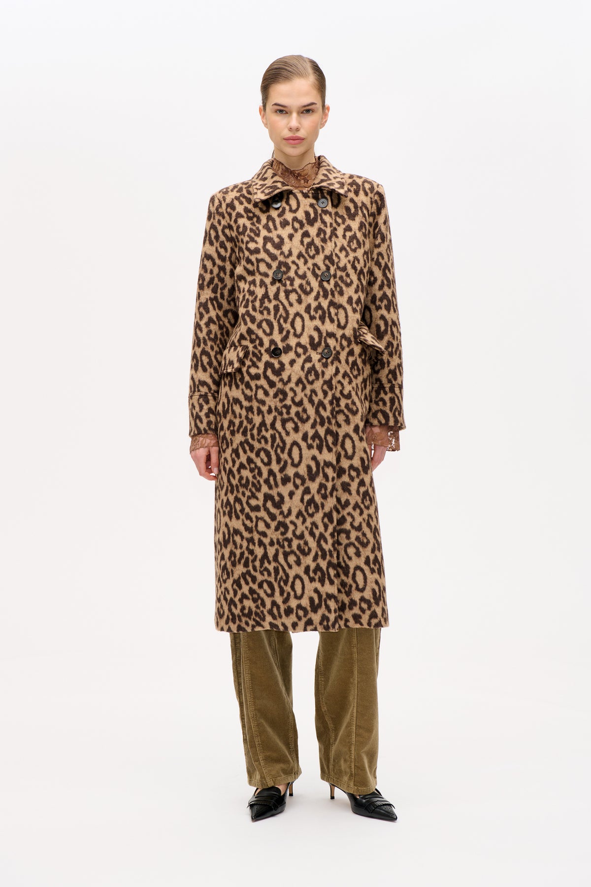 Front view of a model wearing a long camel and dark brown leopard-print double-breasted coat with wide lapels and black buttons.