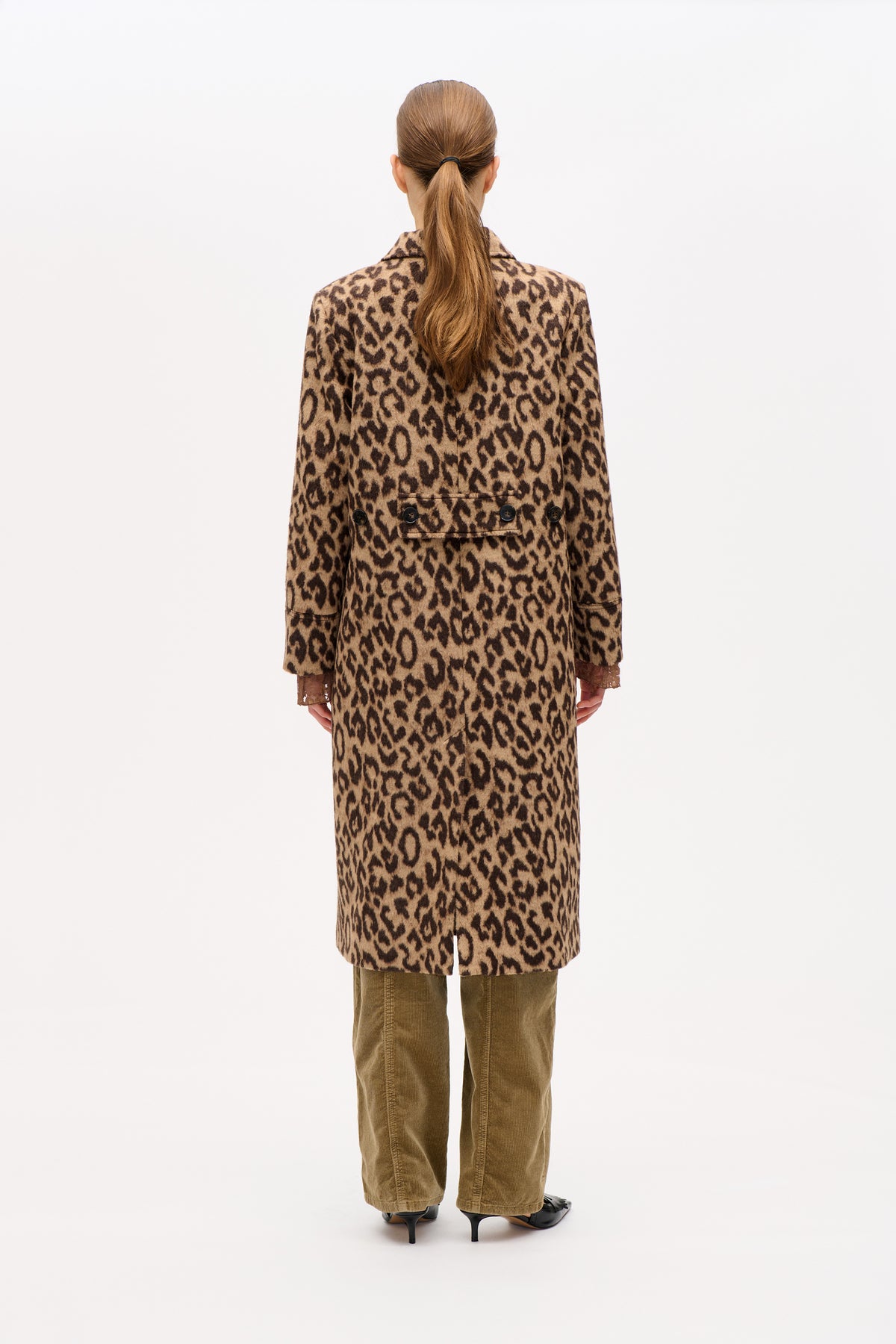 Back view of a model wearing a long beige and dark brown leopard-print coat with a buttoned half belt and side pockets.