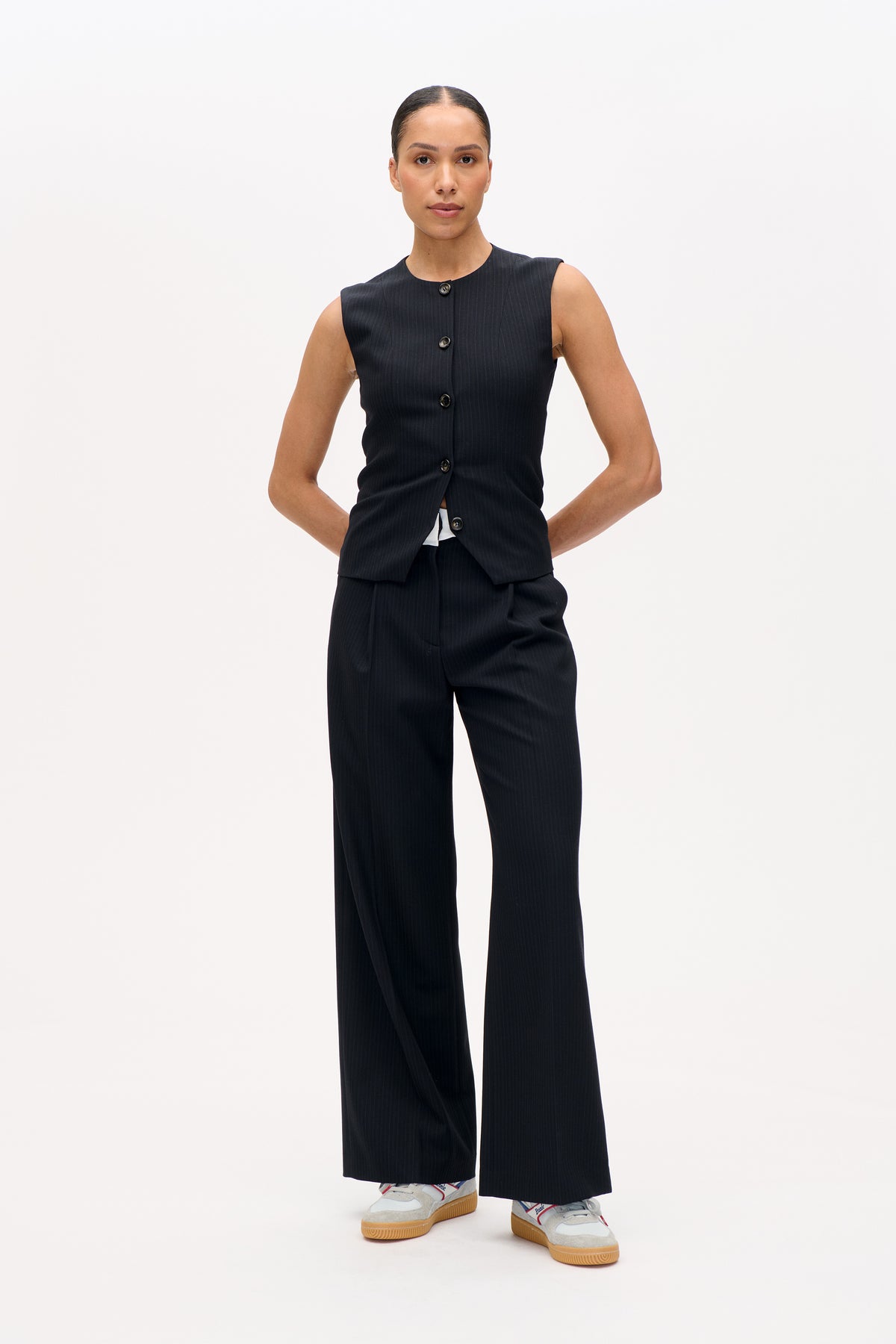 Front view of a dark pinstripe sleeveless button-front vest with matching wide-leg trousers.