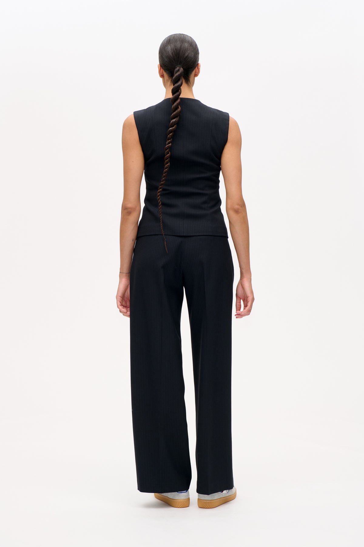 Back view of a model wearing a dark pinstriped sleeveless top with matching wide-leg trousers.