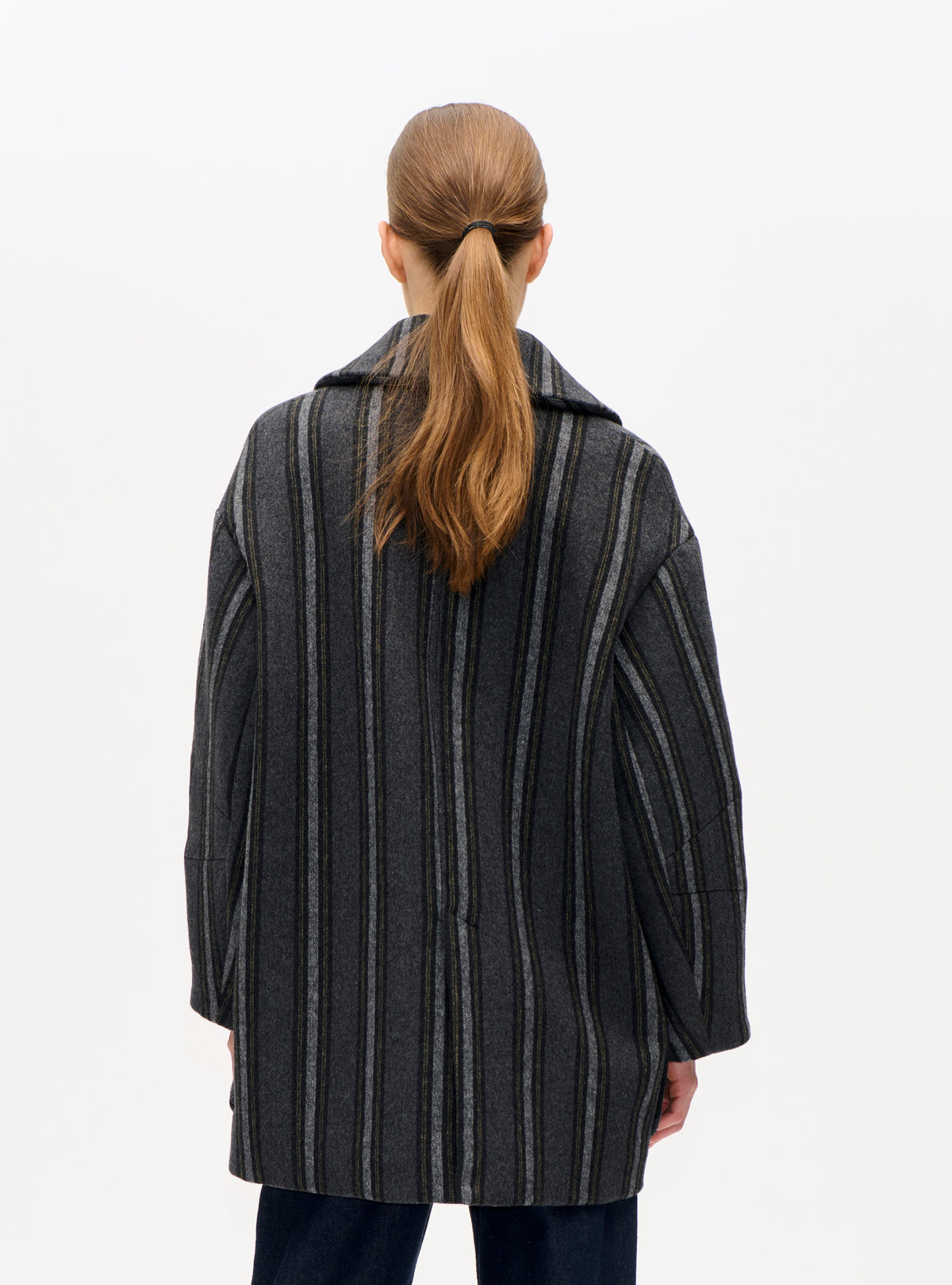 Back view of an oversized charcoal jacket with thin grey and muted olive vertical stripes and a wide lapel.