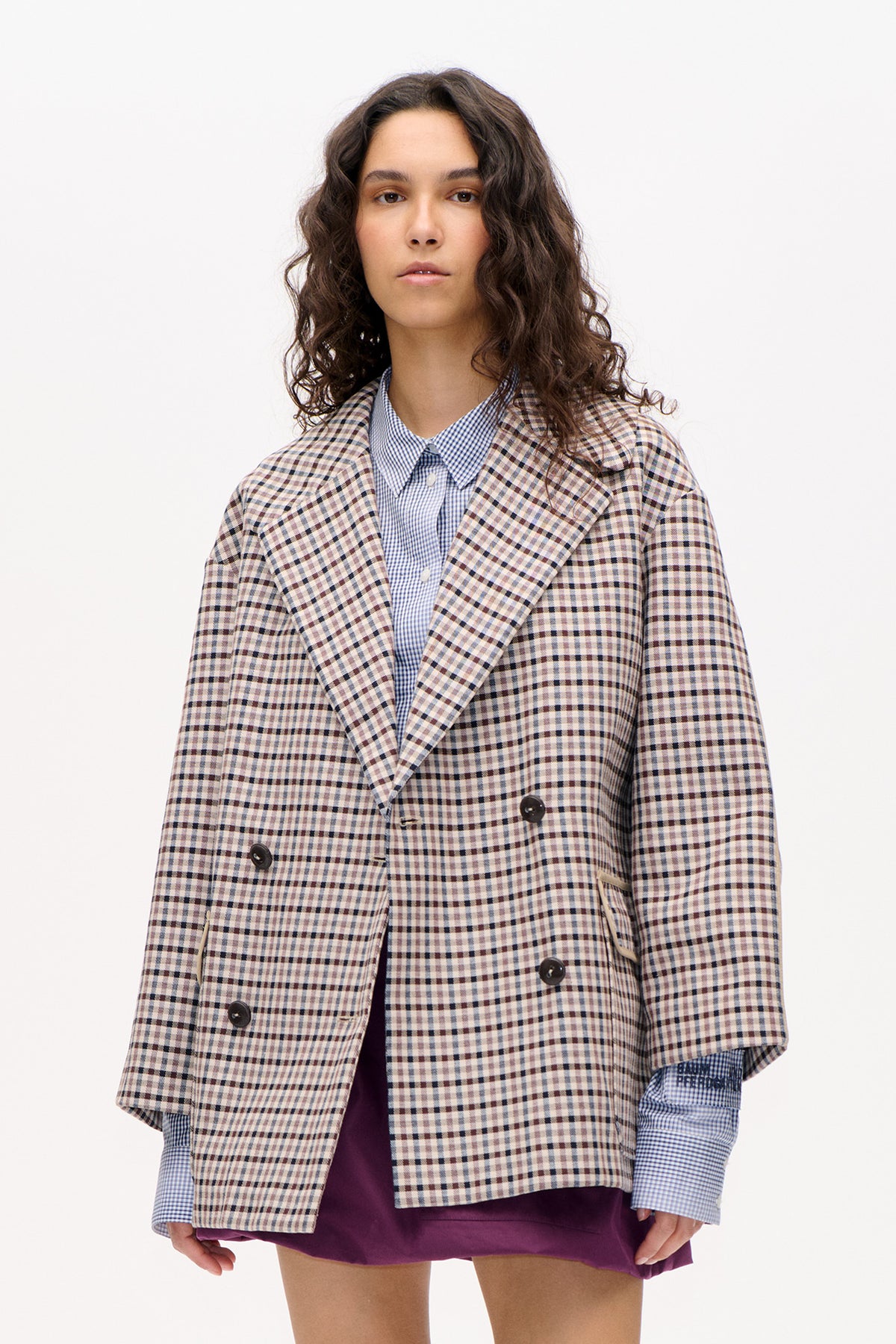 Front view of a model wearing a cream, blue and dark brown checked blazer over a blue gingham shirt.