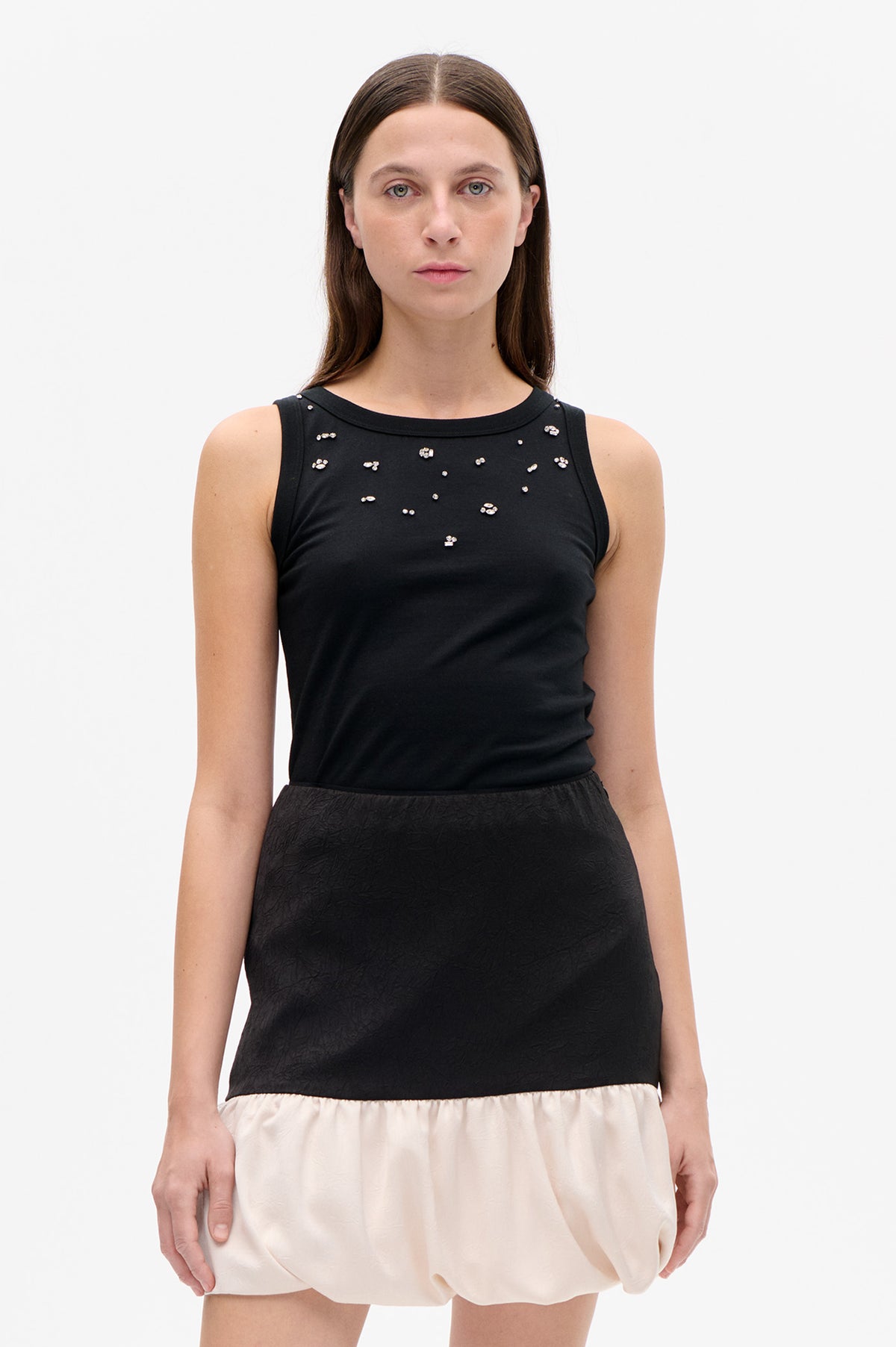 Front detail of a black sleeveless dress with scattered silver embellishments, a textured black waist panel and gathered ivory skirt.