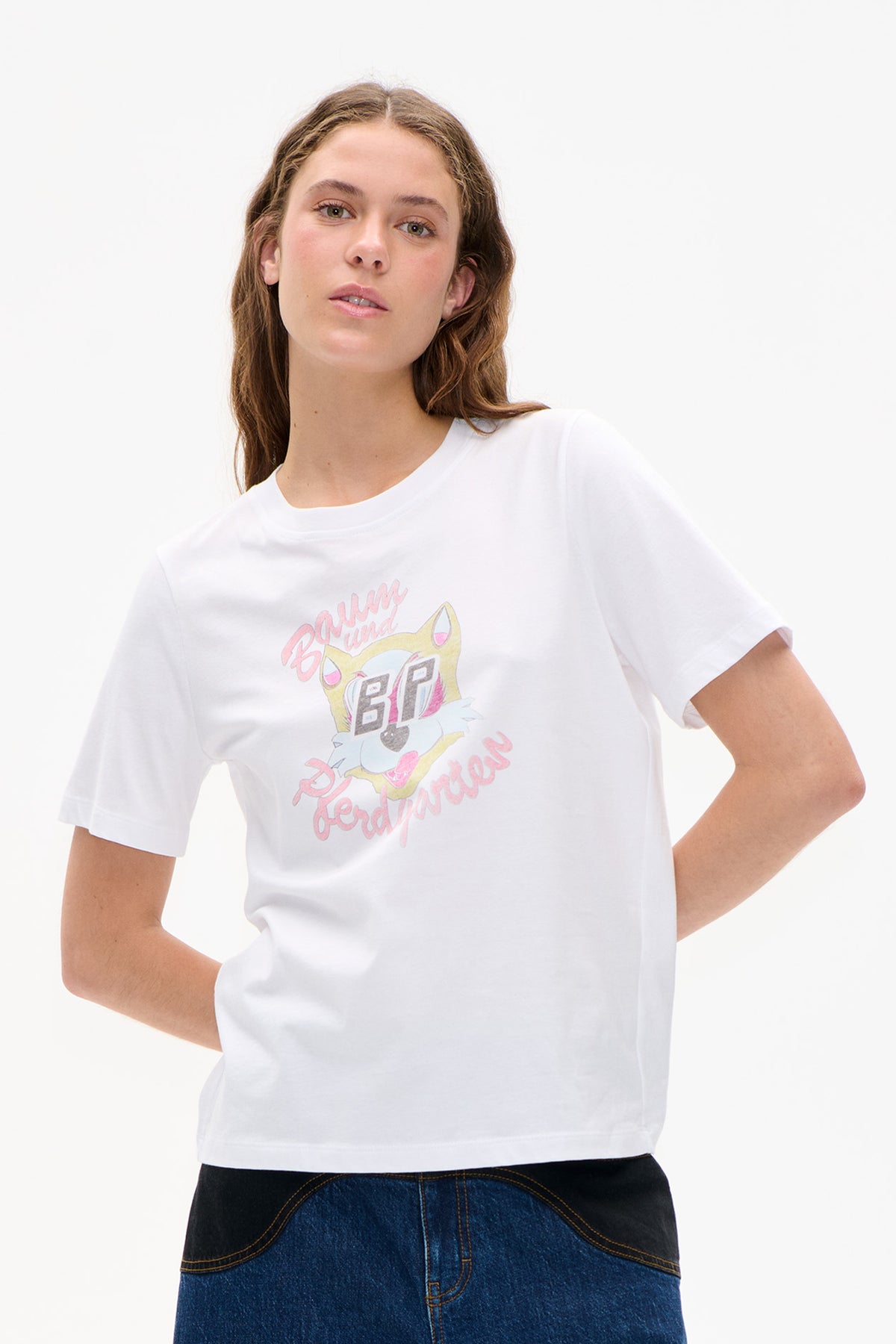 Model wearing a white short-sleeved T-shirt with a colorful cartoon cat and pink lettering graphic.