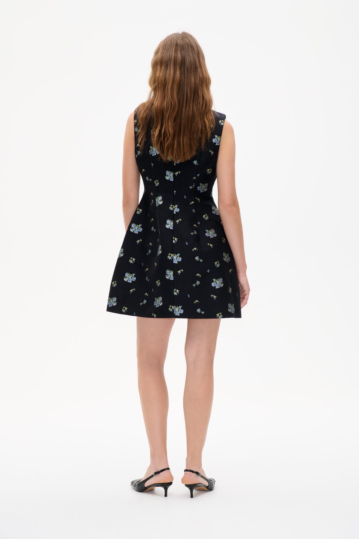 Back view of a sleeveless black fitted mini dress with scattered blue and green floral prints.