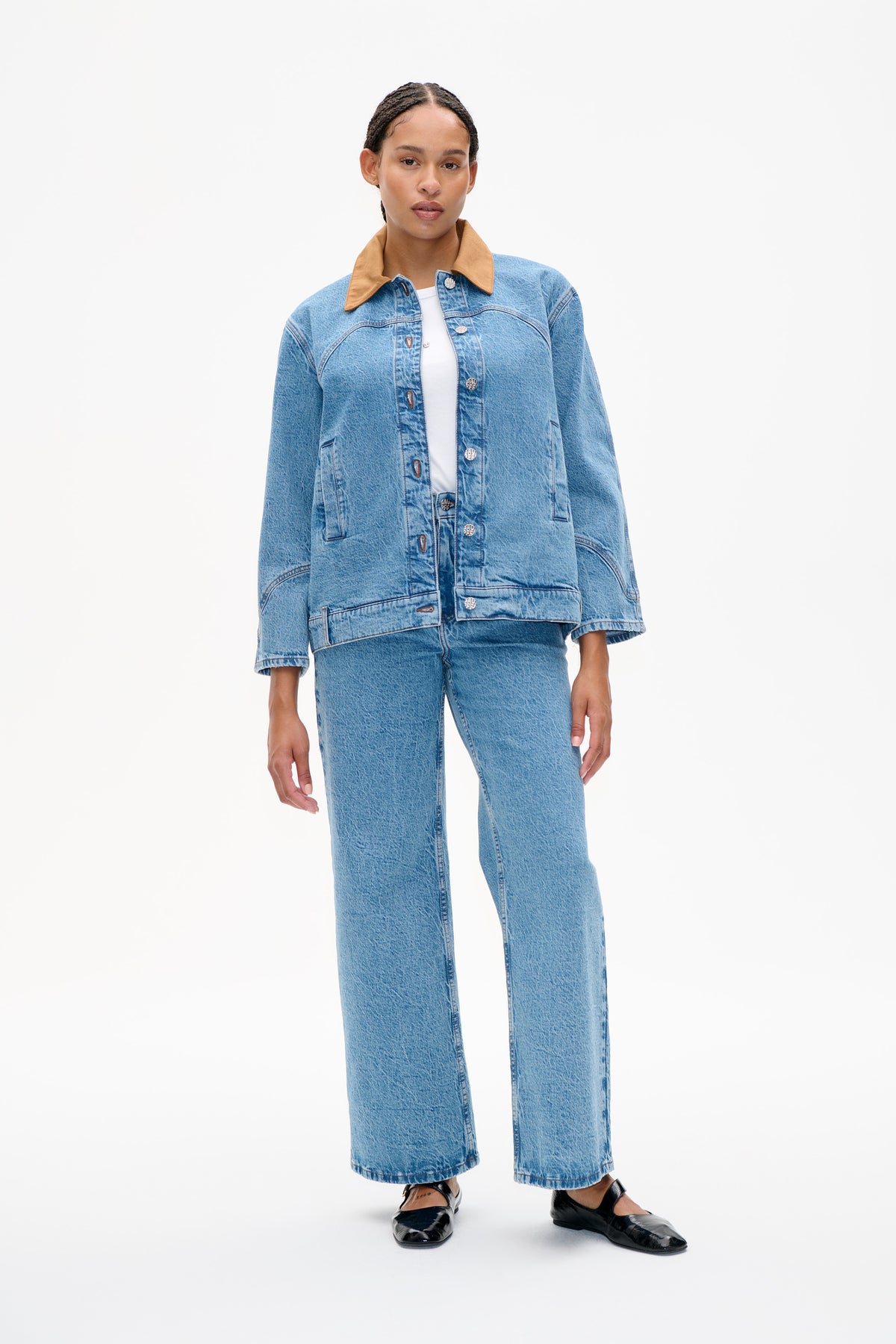Model wearing a light blue denim jacket with a contrasting tan collar and matching wide-leg jeans, shown from the front.