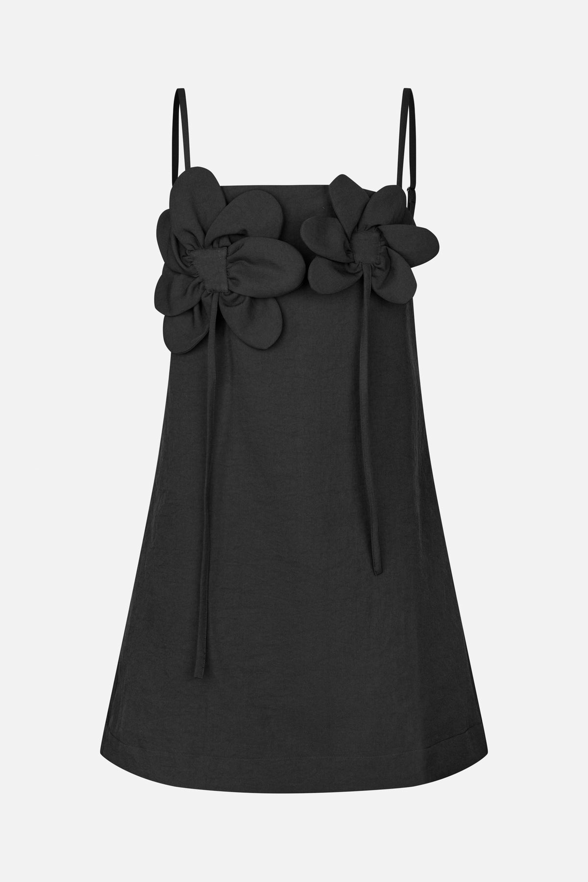 Front view of a black A-line dress with thin straps, oversized layered flower appliqués and long ties at the neckline