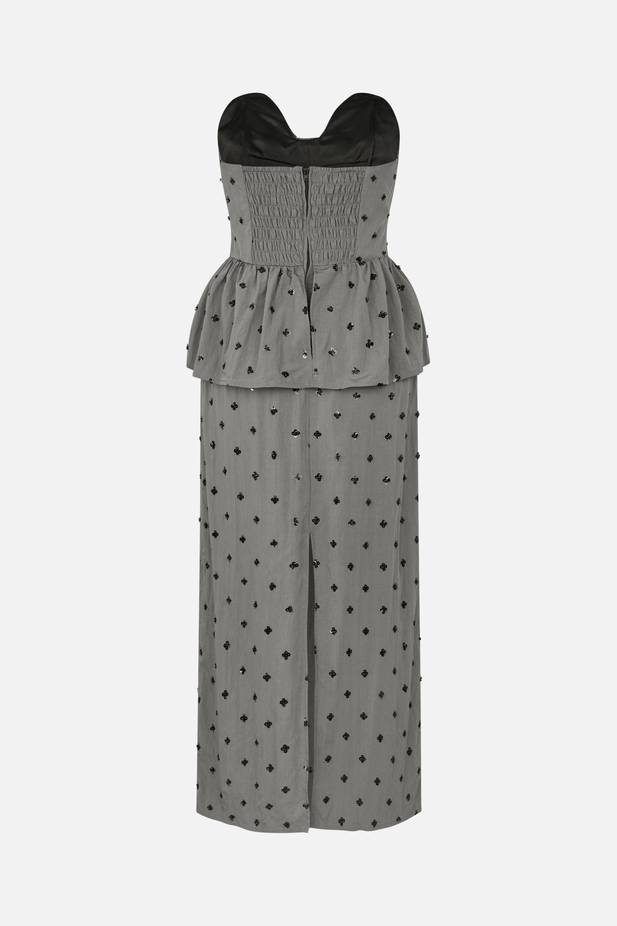 Front view of a grey strapless maxi dress with a ruched bodice, peplum waist, black floral embellishments and a front slit.