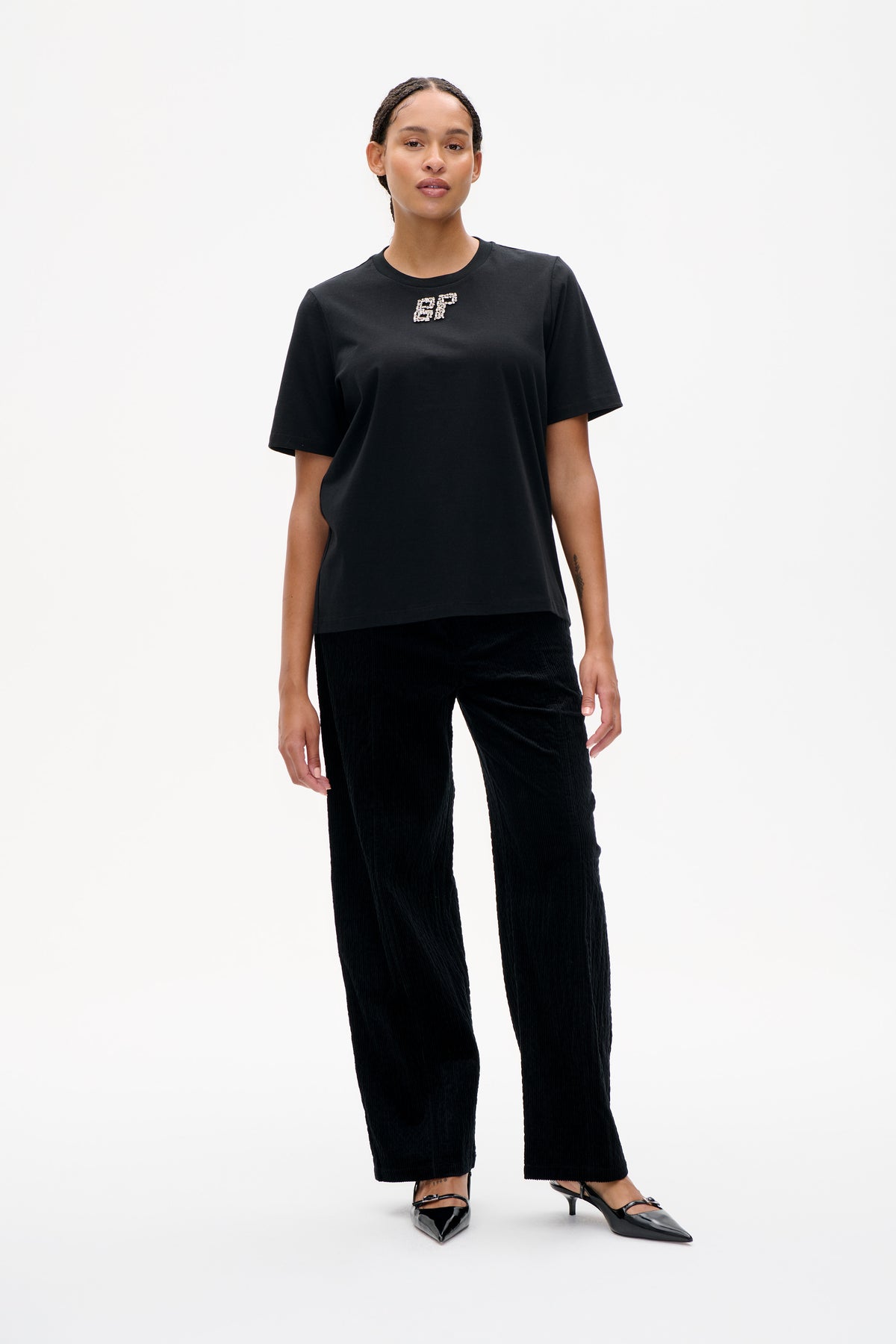 Front view of a black short-sleeve crew-neck T-shirt with sparkling BP initials on the chest, paired with black wide-leg trousers.