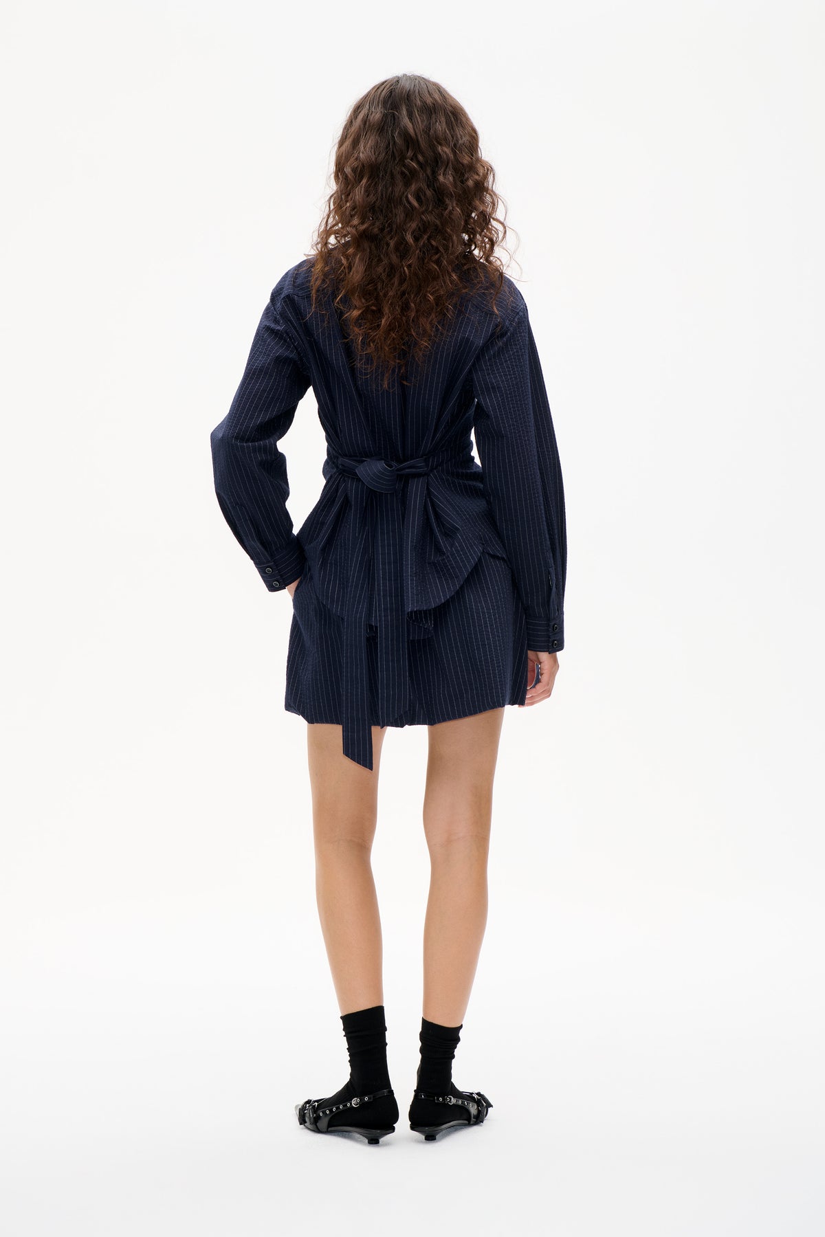 Back view of a navy pinstripe shirt dress with long sleeves and a matching waist tie