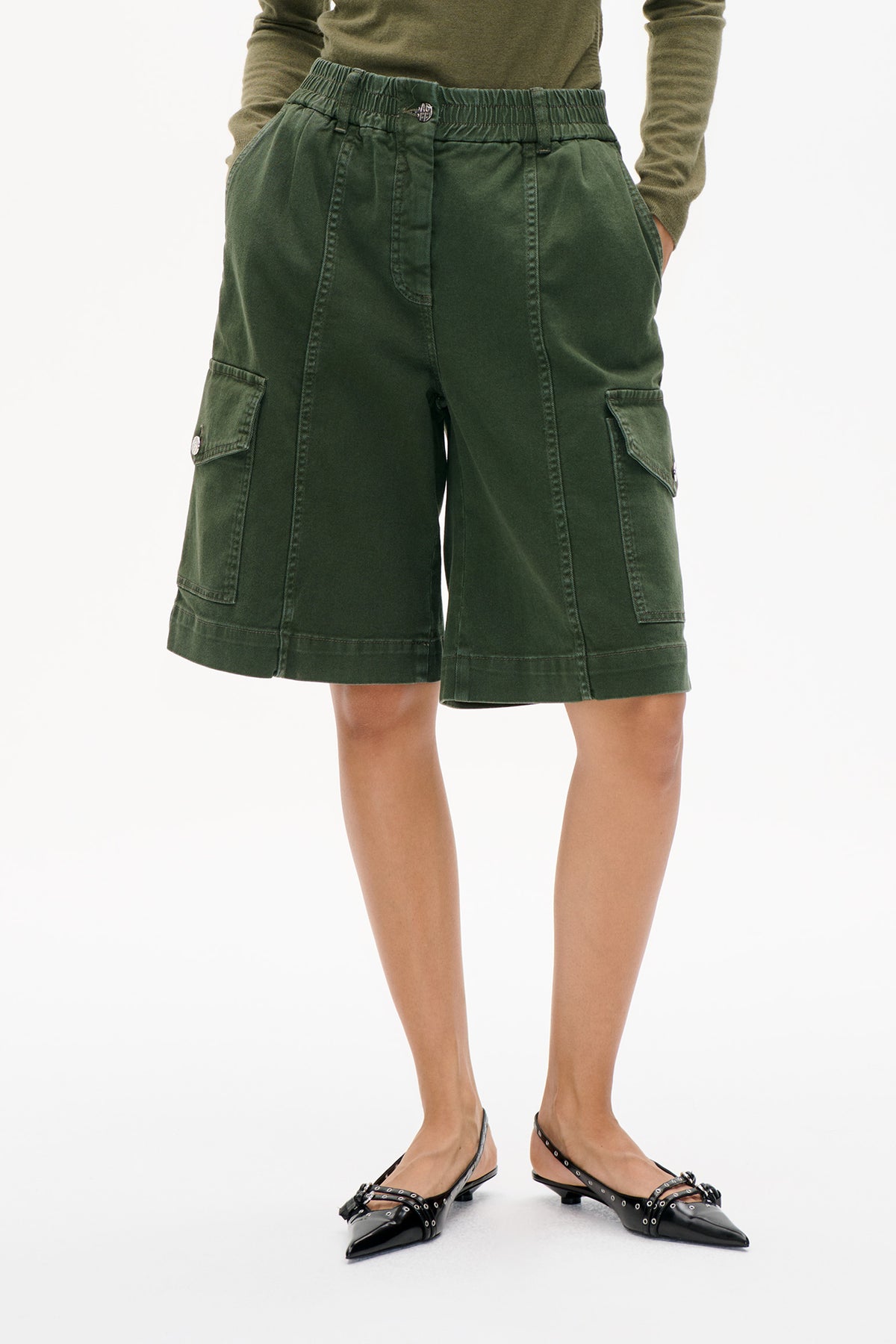 Front detail of dark olive-green cargo shorts with an elasticated waistband, stitched panels and large flap pockets.