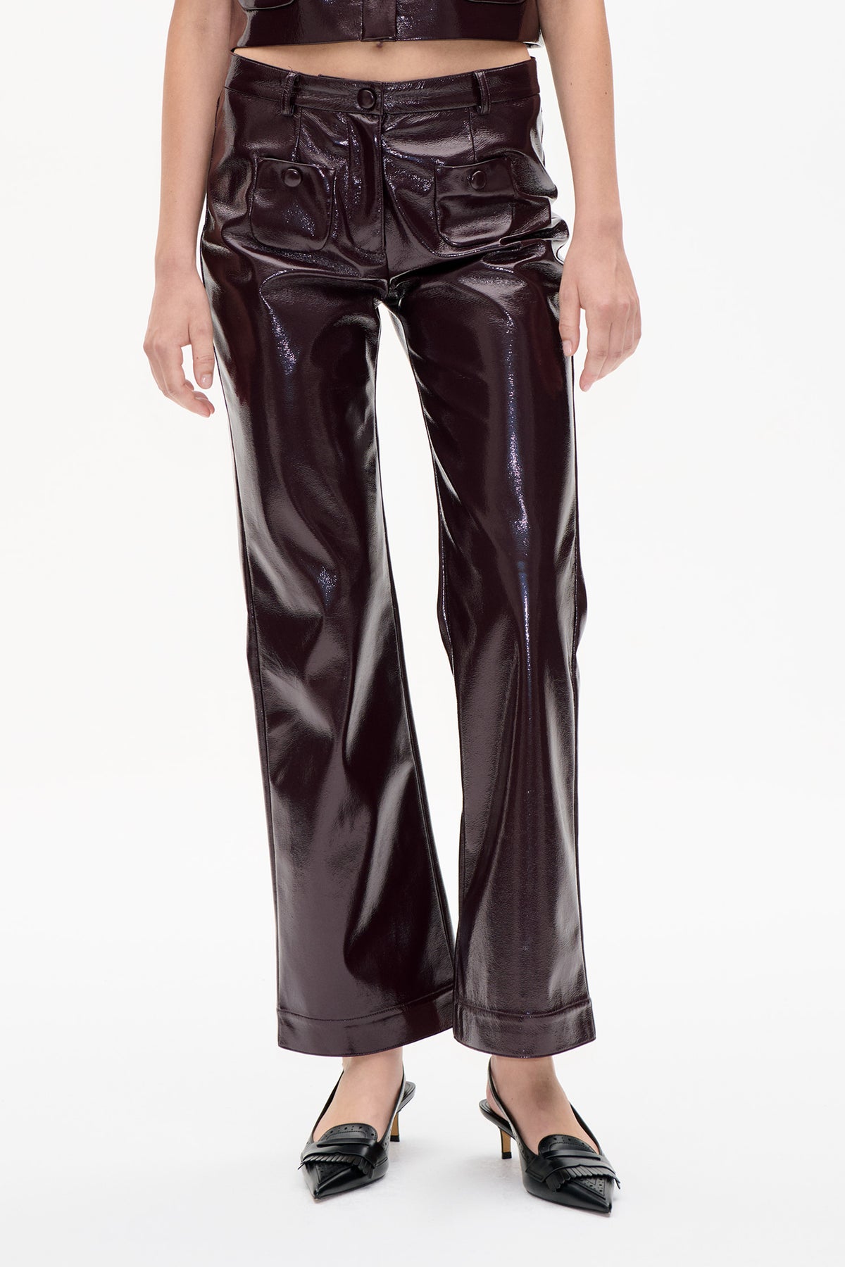 Front detail of glossy dark brown wide-leg trousers with a buttoned waistband and oversized patch pockets, styled with a matching cropped top.