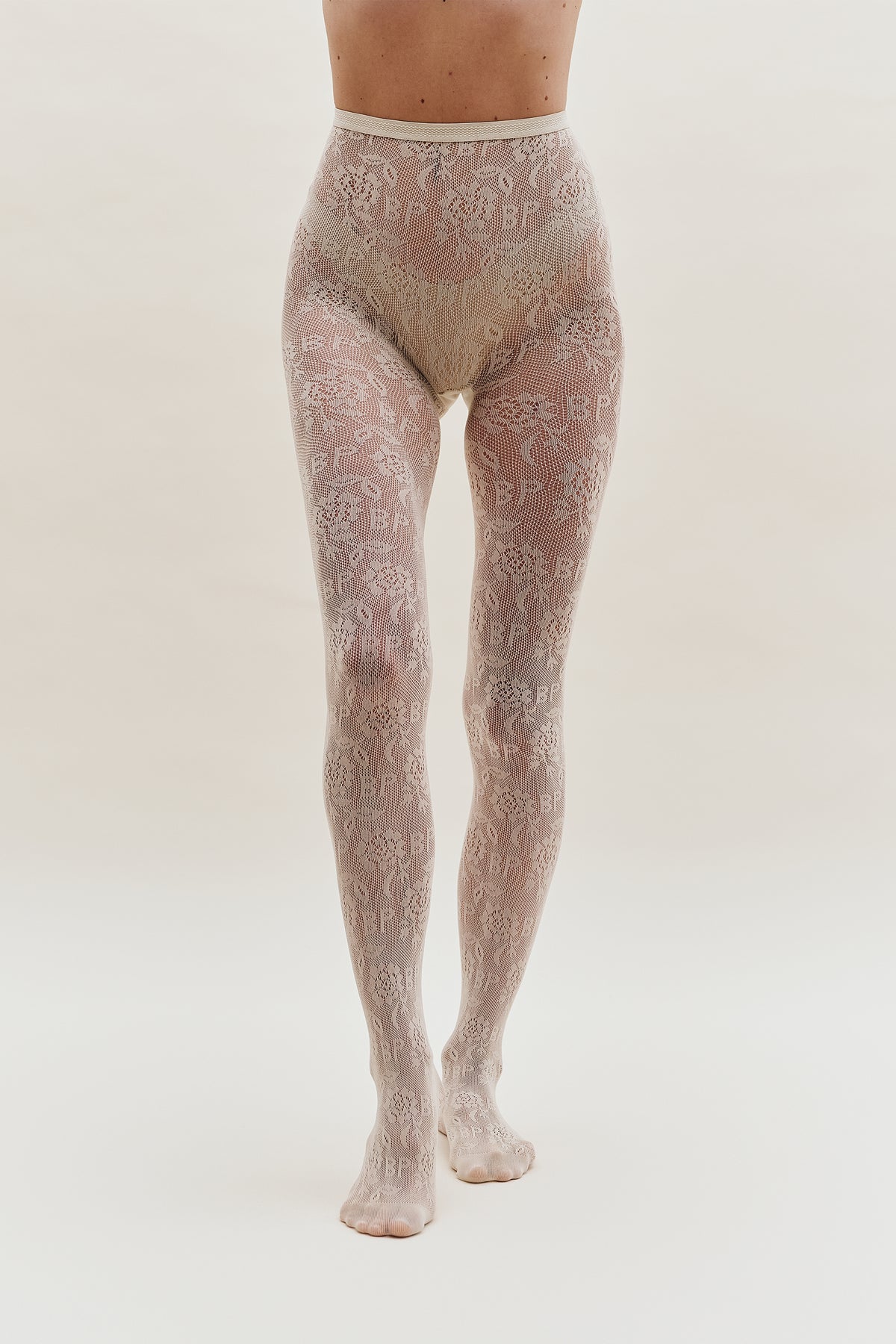 Pale blush lace tights with an all-over floral pattern and repeated lettering, shown from waist to feet