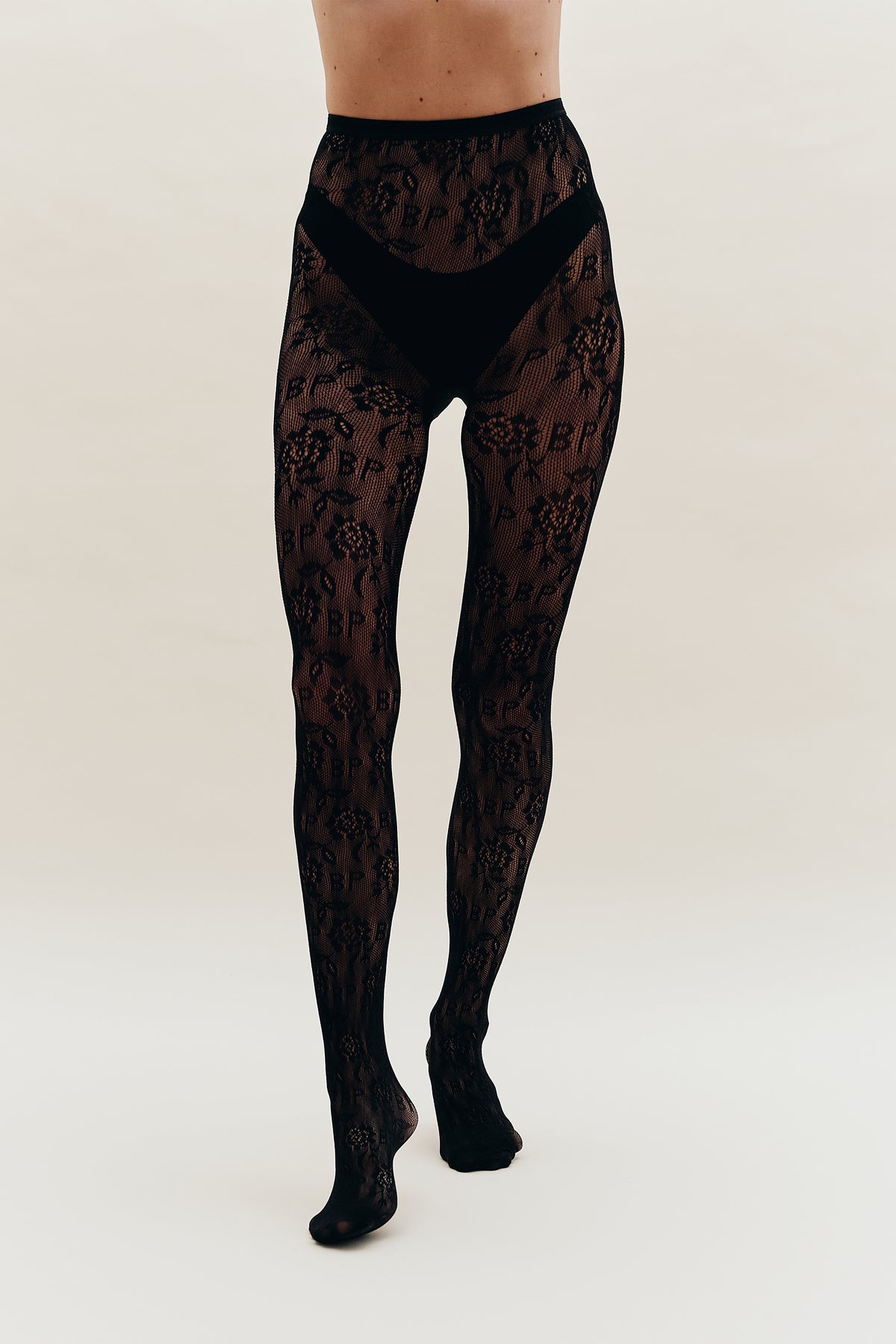 Front view of black sheer floral lace tights with a solid waistband and opaque brief panel