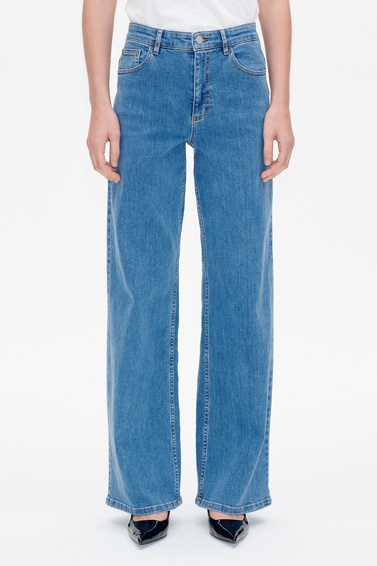 Front view of wide-leg blue jeans with a buttoned waist, curved front pockets and contrast stitching, worn with a white top.