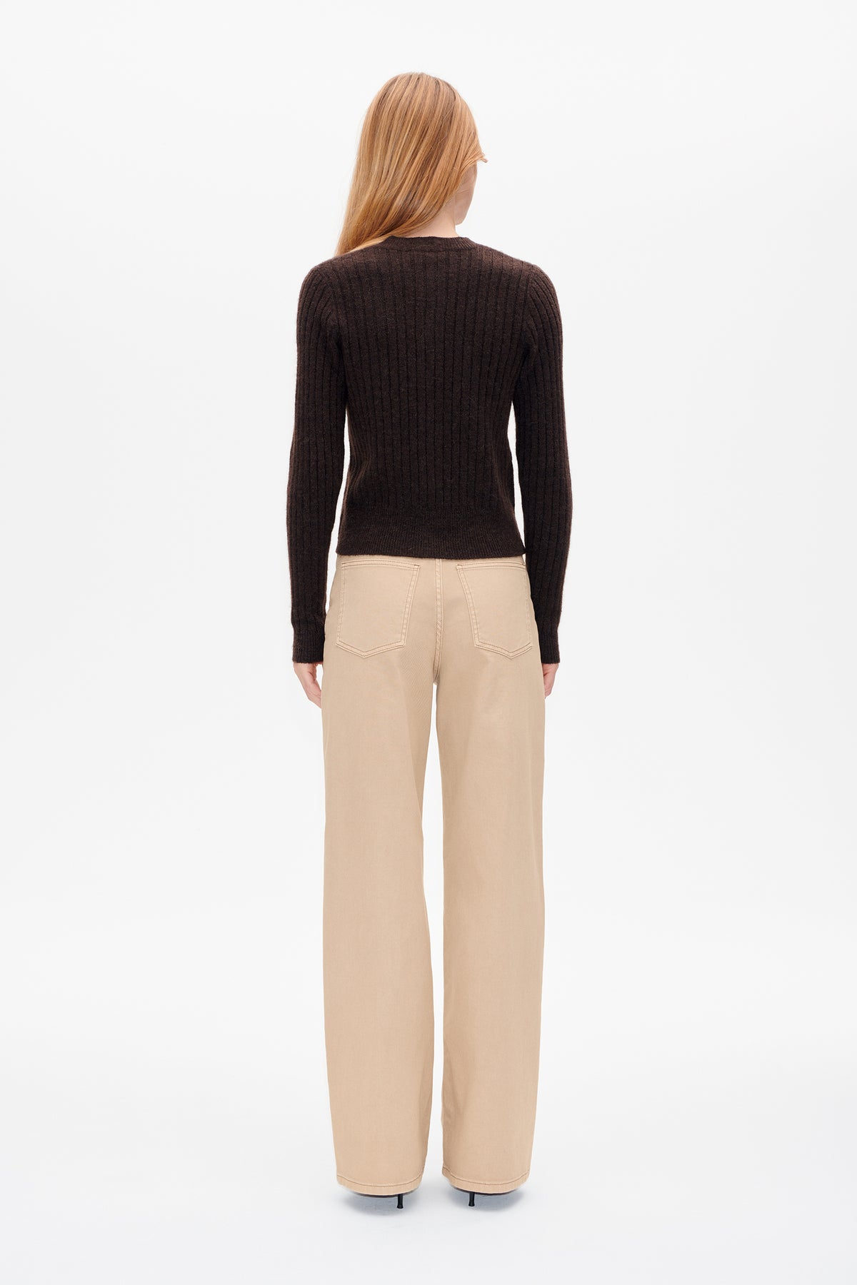 Vue de dos d'une mannequin portant un pull côtelé à manches longues brun foncé et un pantalon large beige.