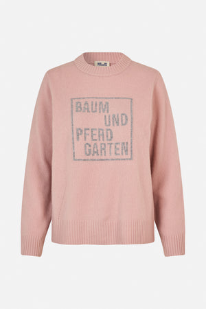 Pink long-sleeved knit sweater with a ribbed crew neck, cuffs and hem, featuring a large grey Baum und Pferdgarten logo on the front.