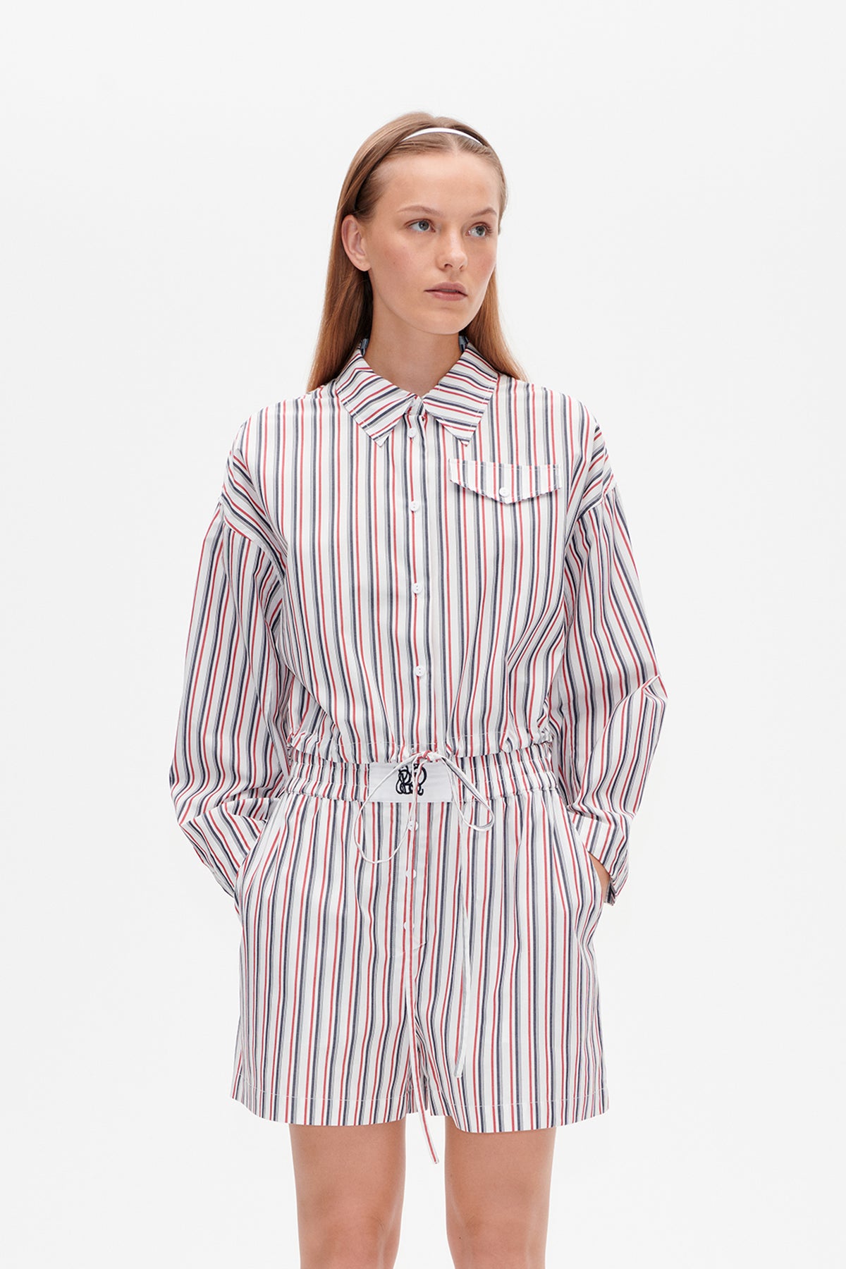 Vorderansicht eines weißen Hemdes mit Knopfleiste und passender Shorts mit roten, marineblauen und grauen Streifen, Brusttasche und Kordelzugbund.