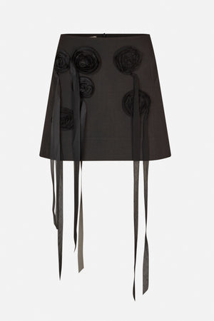 Front view of a black A-line mini skirt with raised fabric rosettes and long hanging ribbon details.