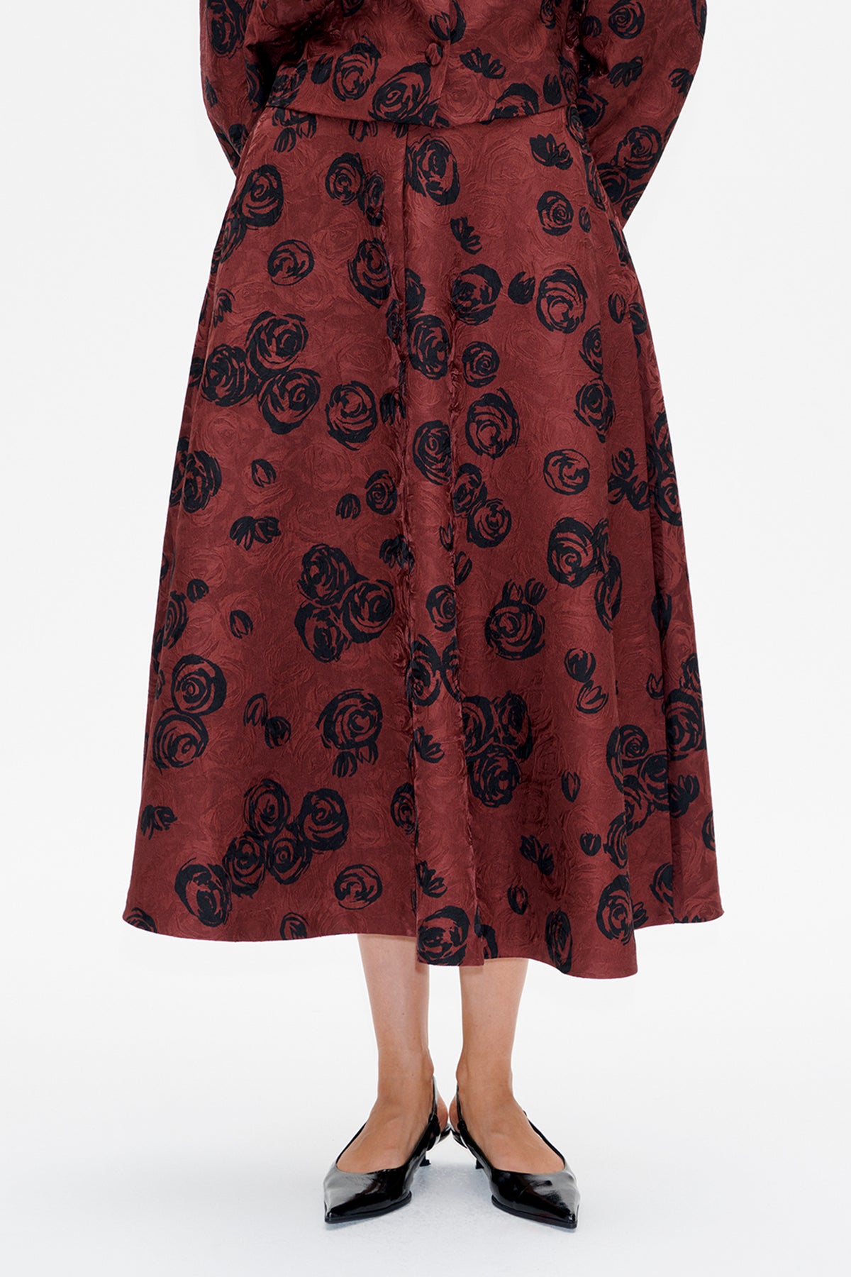 Front detail of a burgundy dress with an allover black rose print and softly gathered skirt.