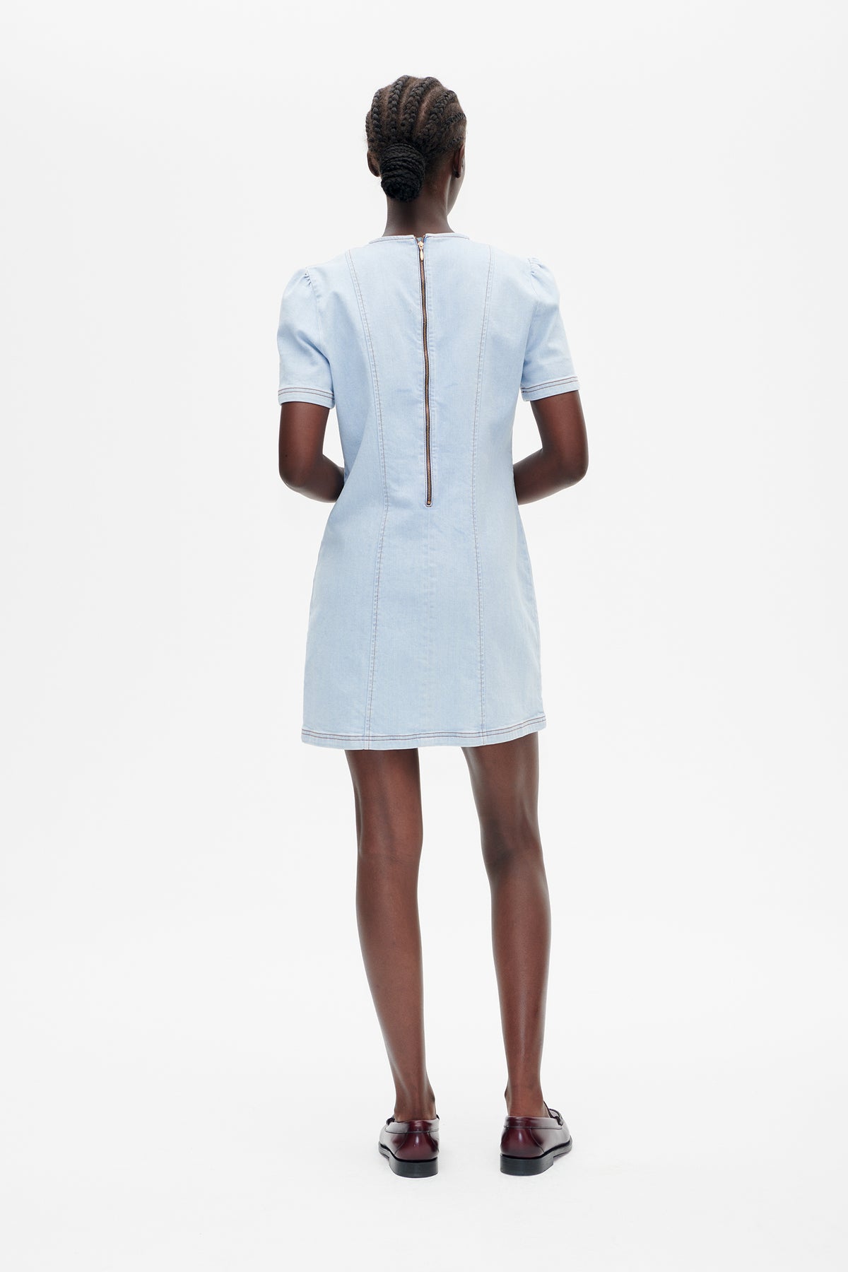 Back view of a light blue short-sleeved denim dress with a central zipper and contrast stitching.