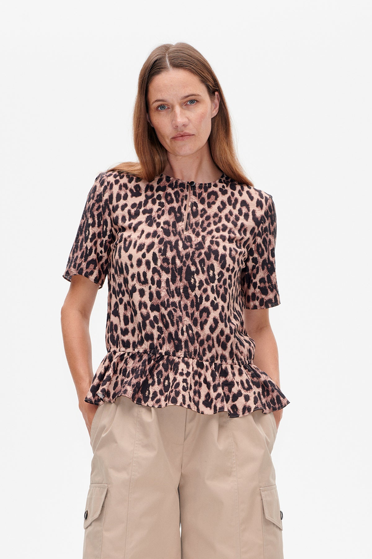 Front view of a short-sleeved blouse with a round neckline, button detail and flared waist, in a pink and black leopard print