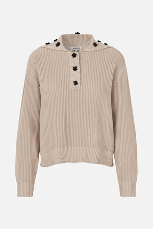 Front view of a beige ribbed knit sweater with a wide collar, black flower-shaped buttons and floral embellishments.