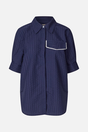 Front view of a dark navy collared shirt with a subtle tonal geometric pattern, short sleeves and a chest pocket edged in white piping.