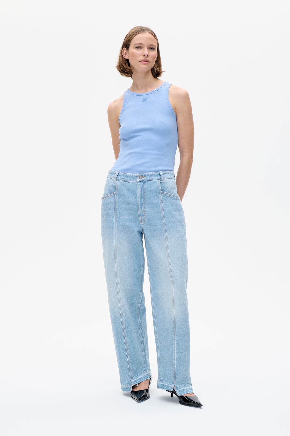 Model wearing a pale blue sleeveless ribbed tank with a small tonal BP chest logo and light-wash wide-leg jeans with frayed hems.
